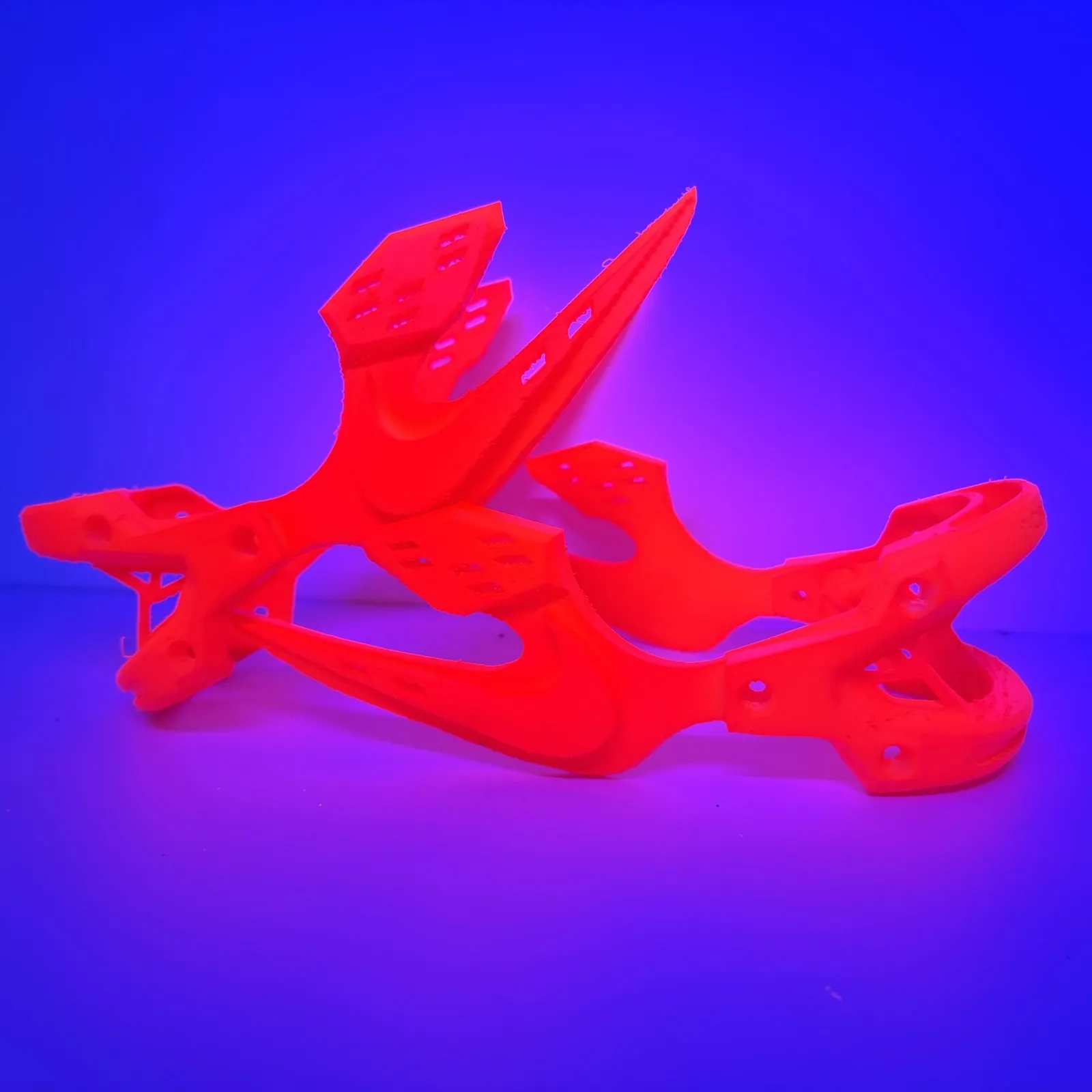 A red resin dragon and bracket lying on its side, glowing under violet UV light