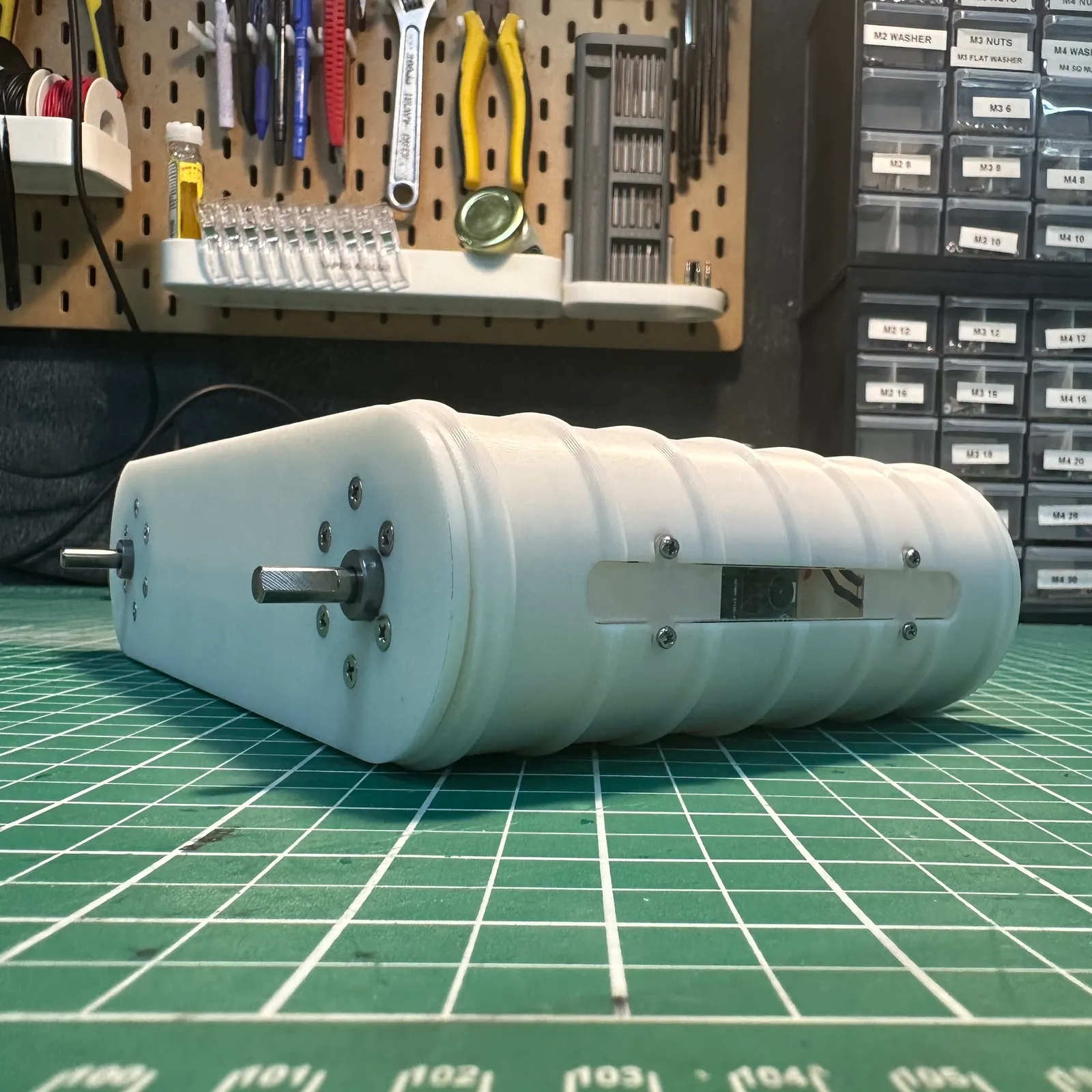 The long side of the ribbed white housing with a clear window screwed into it, and a motor shaft at the far end