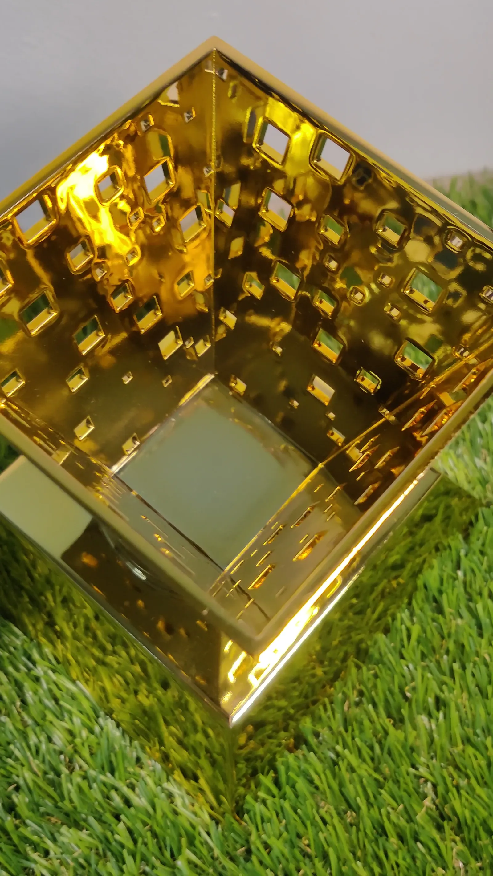 Looking down into the gold urn: its plated inner walls, the square cut-outs and the base below