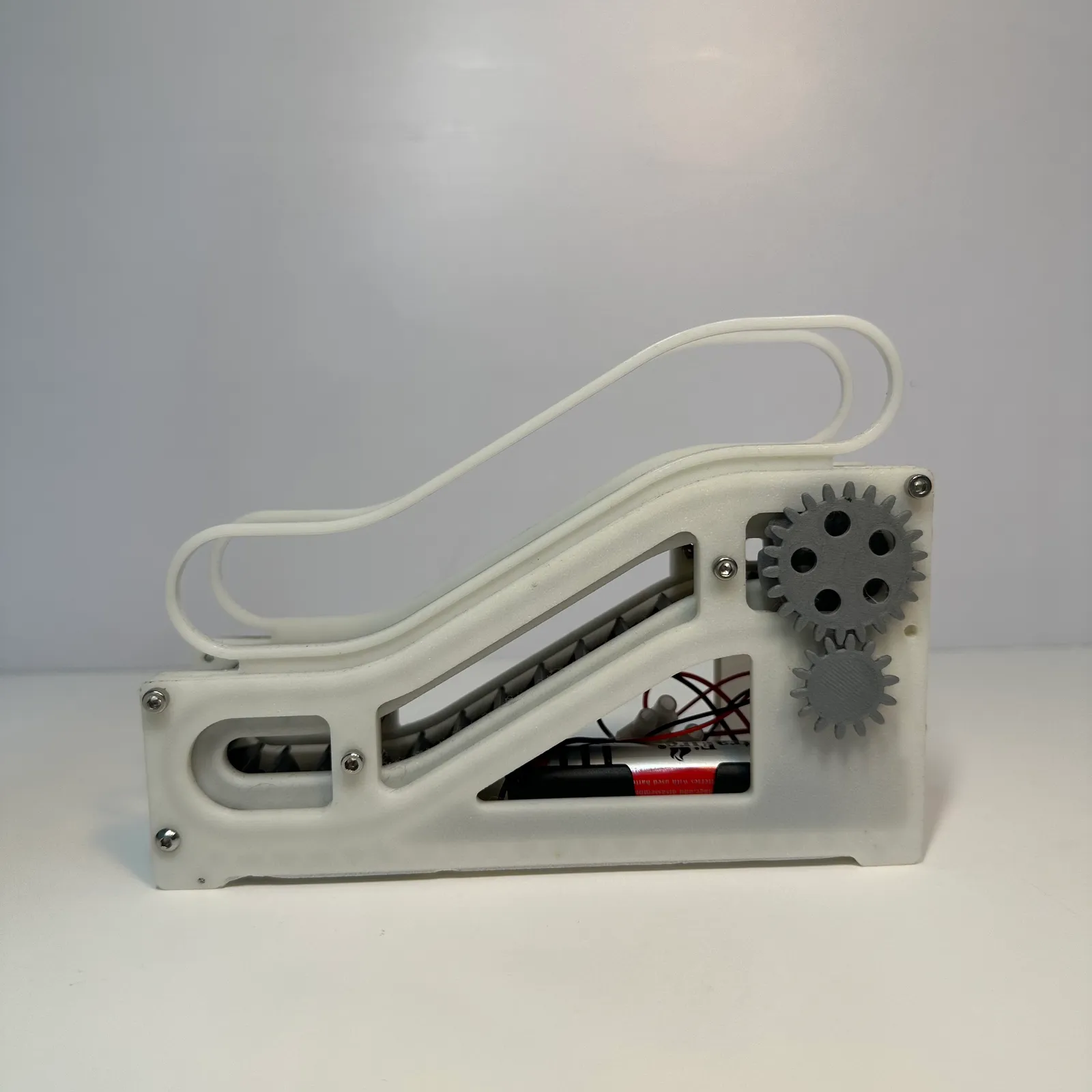 Side profile of the finished escalator model: the white side frame with its cut-outs, the handrail loop on top and the two gears at the upper end