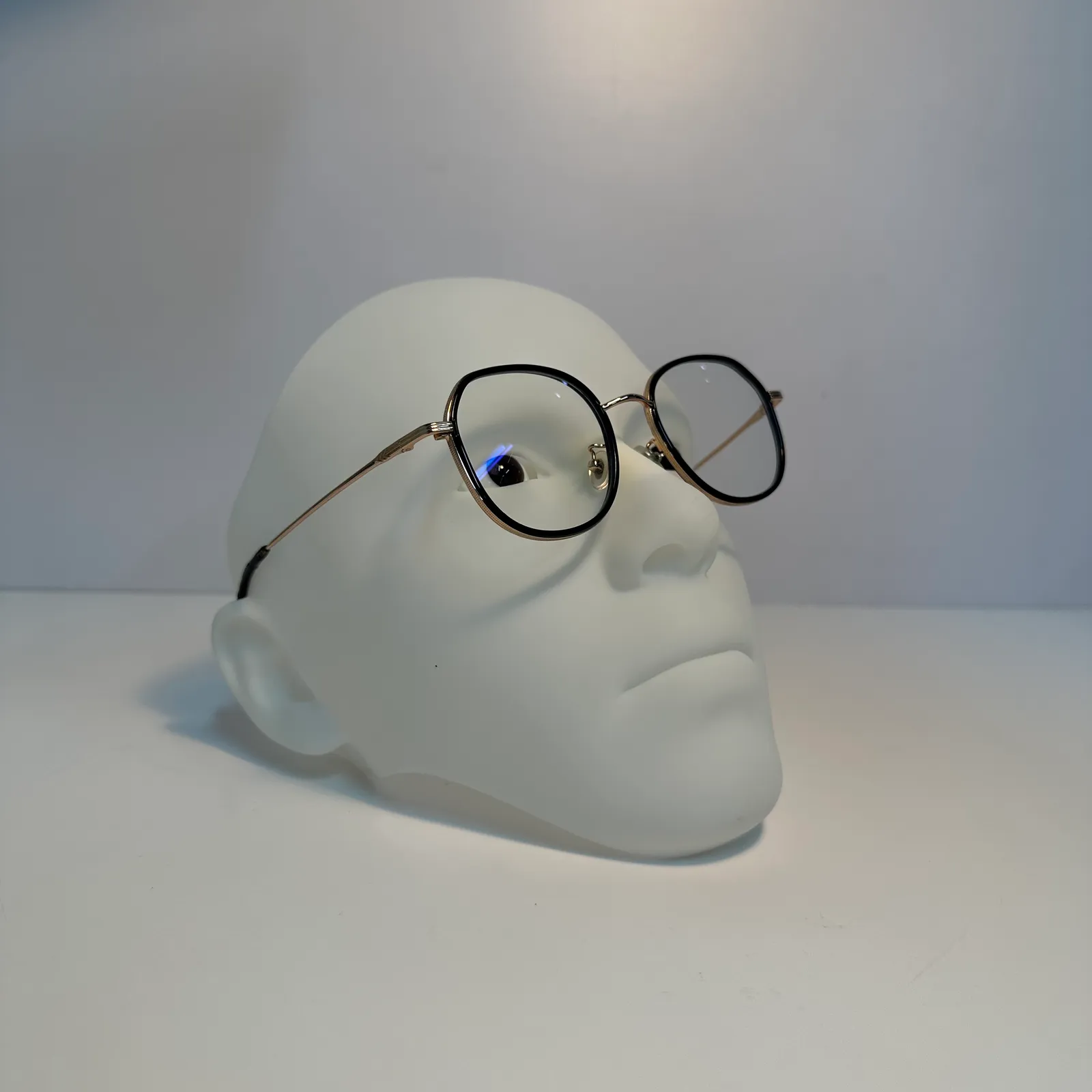 The face tilted back in side view, the spectacles sitting on the nose and the arm resting over the ear