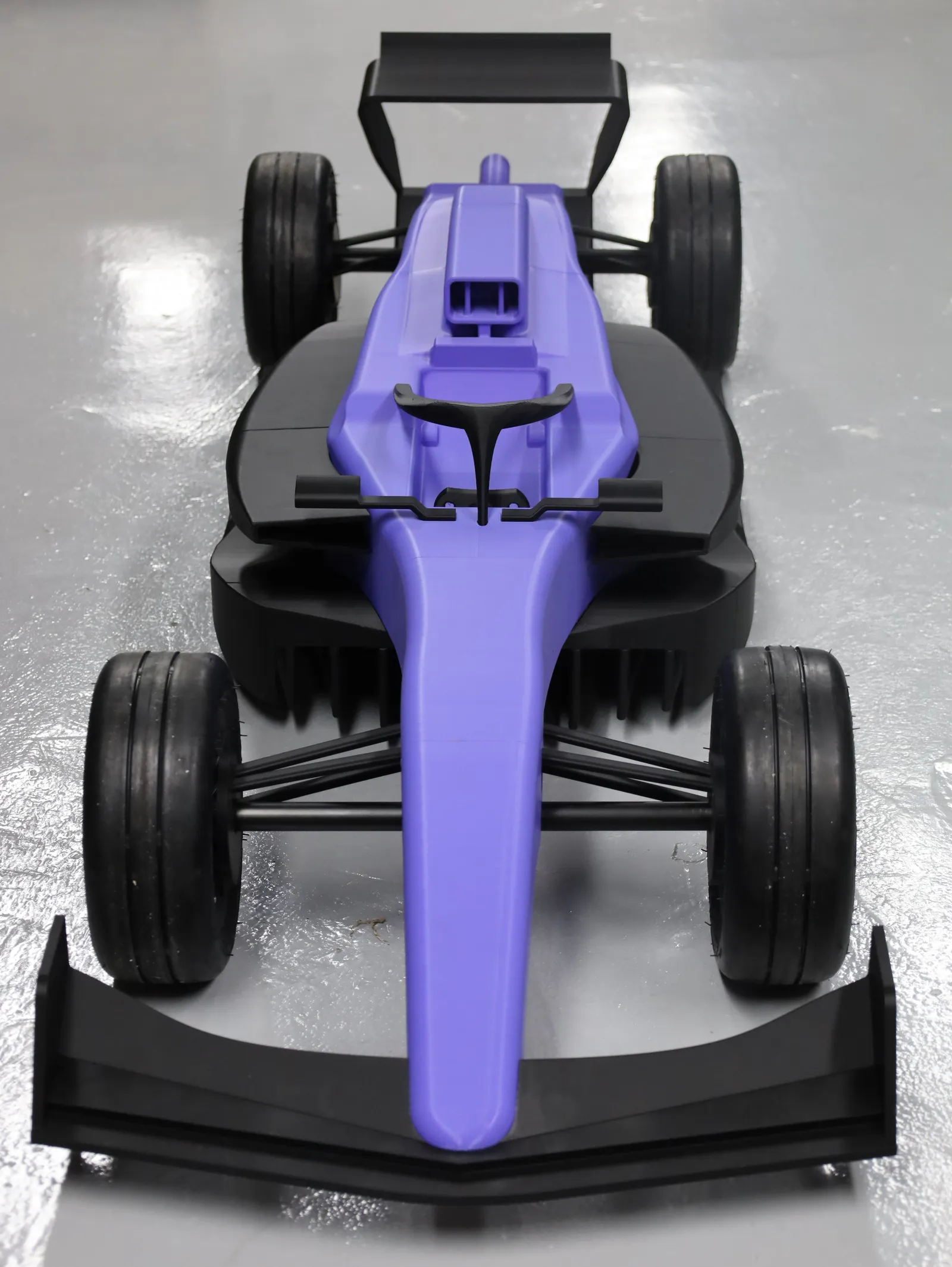 The finished show car seen head-on from above: purple nose and halo, black front wing, sidepods and rear wing, and four black wheels
