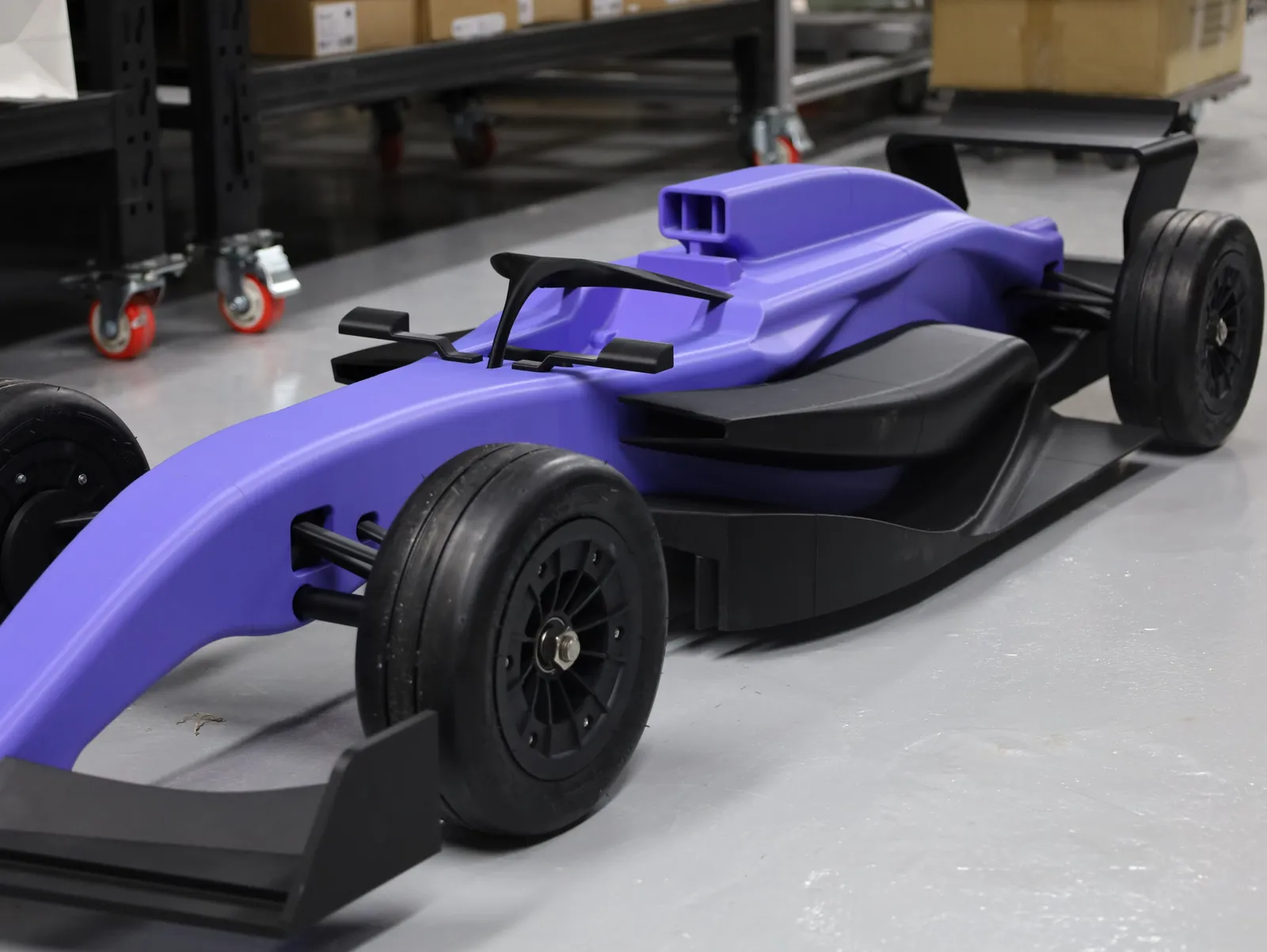 Low front corner view of the finished car: front wheel and suspension arms, the halo, air intake and black sidepod
