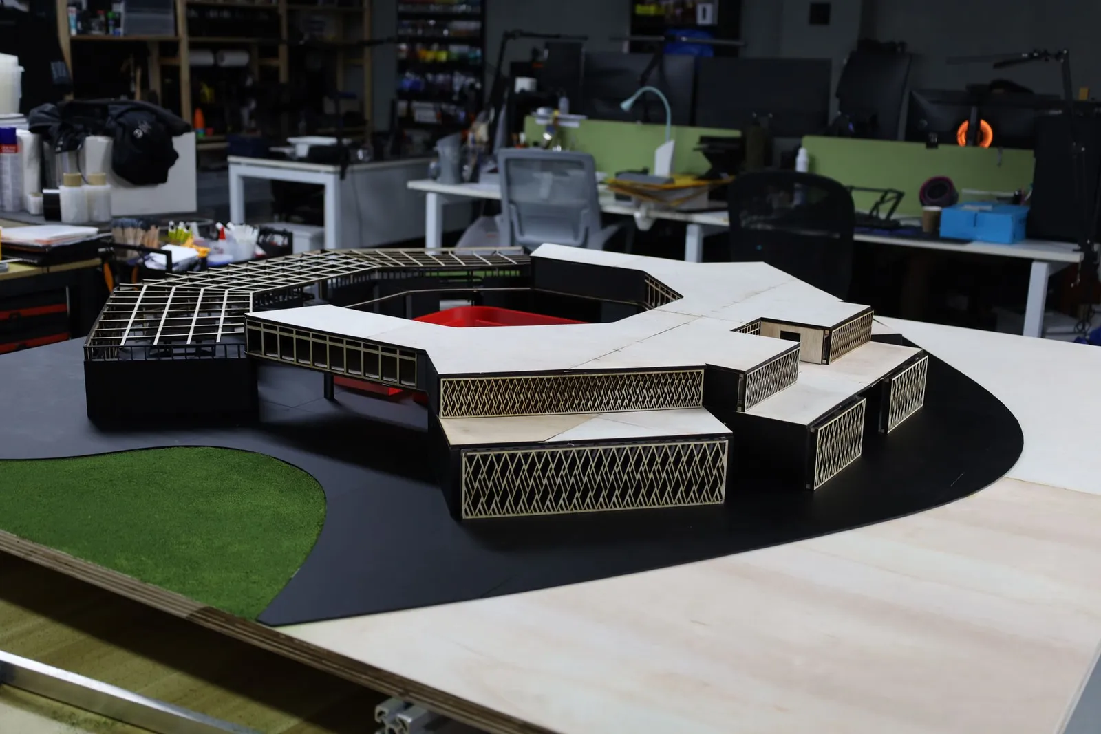 The finished model from the front left: plywood roofs and diamond-lattice screens on the faceted wings, with the open roof grid behind
