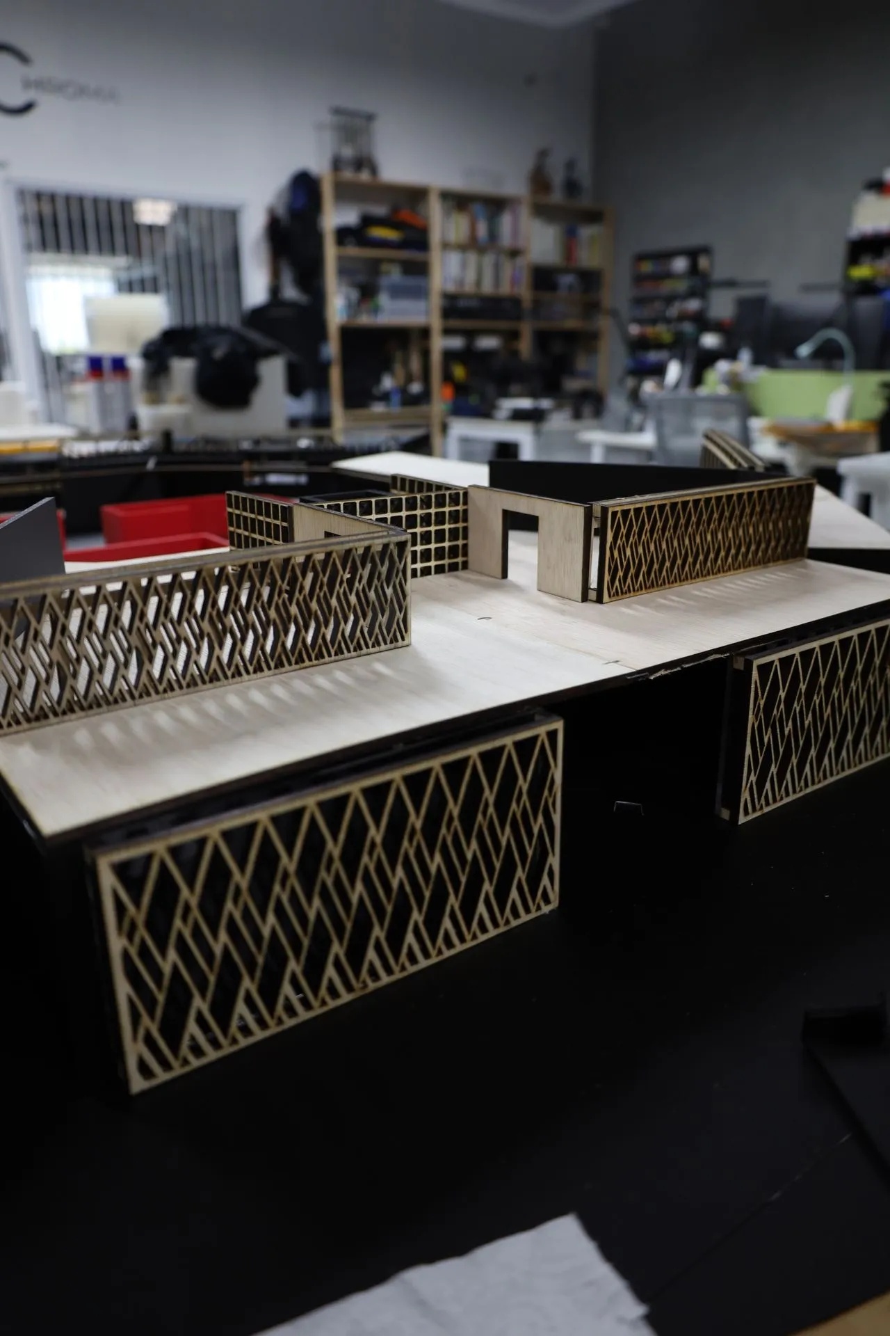 The partly built model: diamond-lattice screens and the plywood roof of one wing fitted, with the upper level still being added