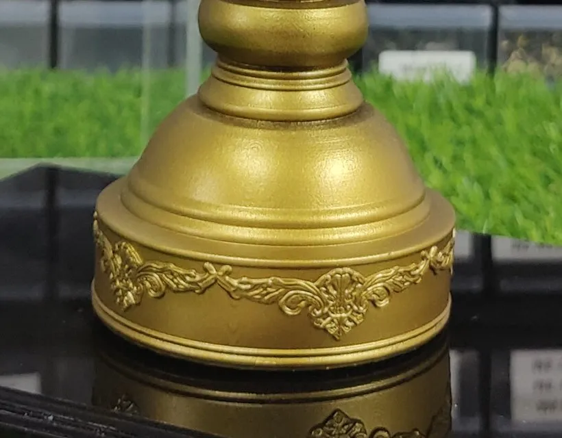 Close-up of the replica's stepped foot with a band of raised leaf ornament round it, in matte gold on the black base