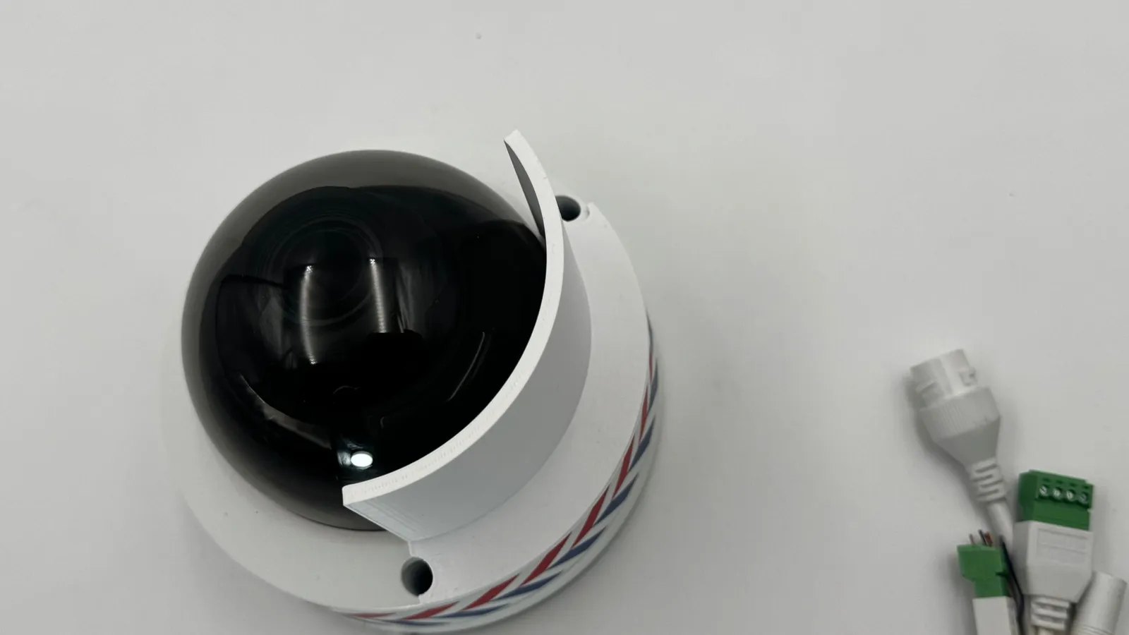 Looking down on the camera: the white shield curving around one side of the black dome, a screw hole open beside it