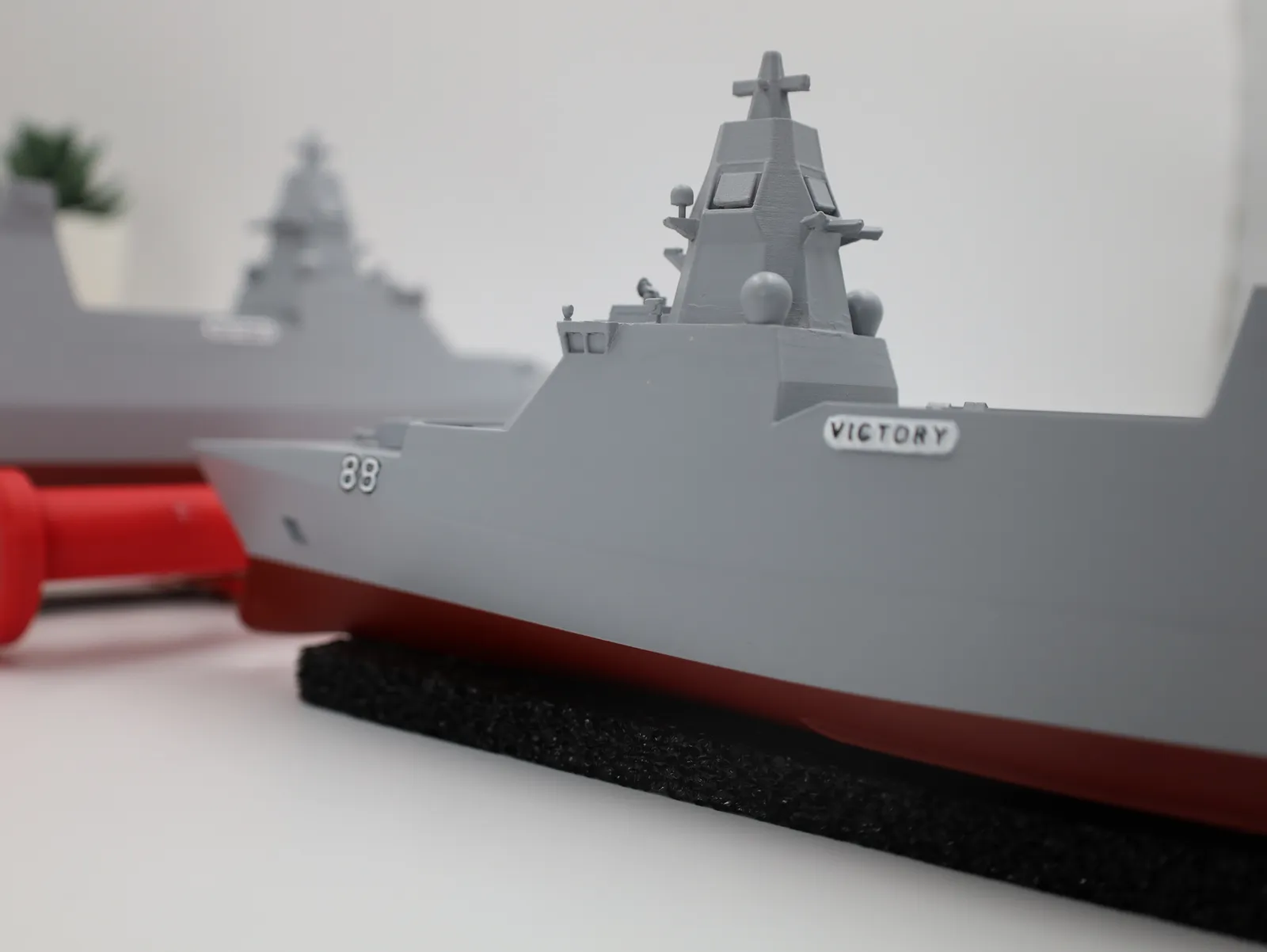 A close view of the bow of one model, showing 88 on the hull, the VICTORY nameplate and the red lower hull on a black stand