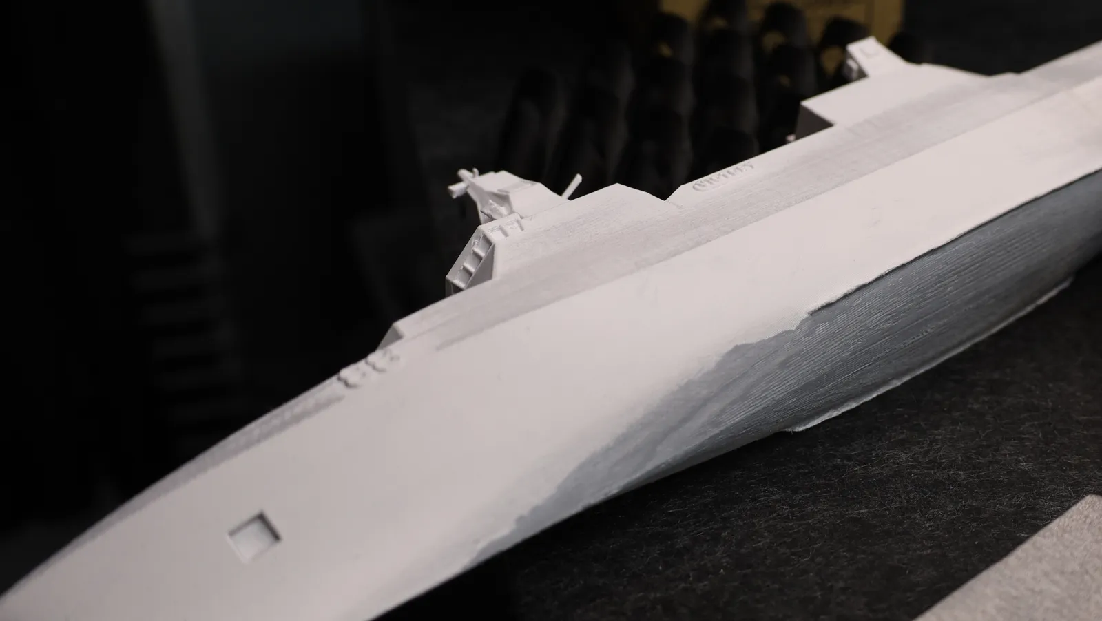 The printed hull on the bench, its upper half primed white and the lower hull still showing grey print lines