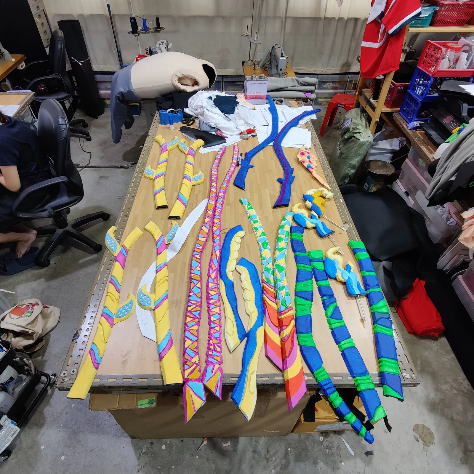 Painted antler parts in stripes of yellow, blue, pink and green laid out on a long workbench