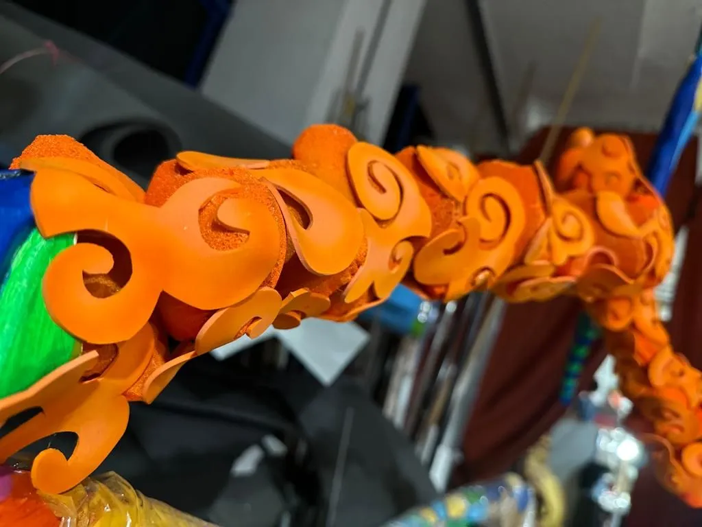 Close-up of a branch covered in raised orange cloud scrolls, painted by hand