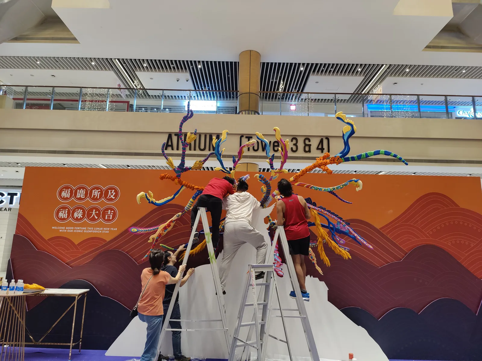 Our team on two ladders mounting the antlers on the Glenfiddich backdrop in the mall atrium
