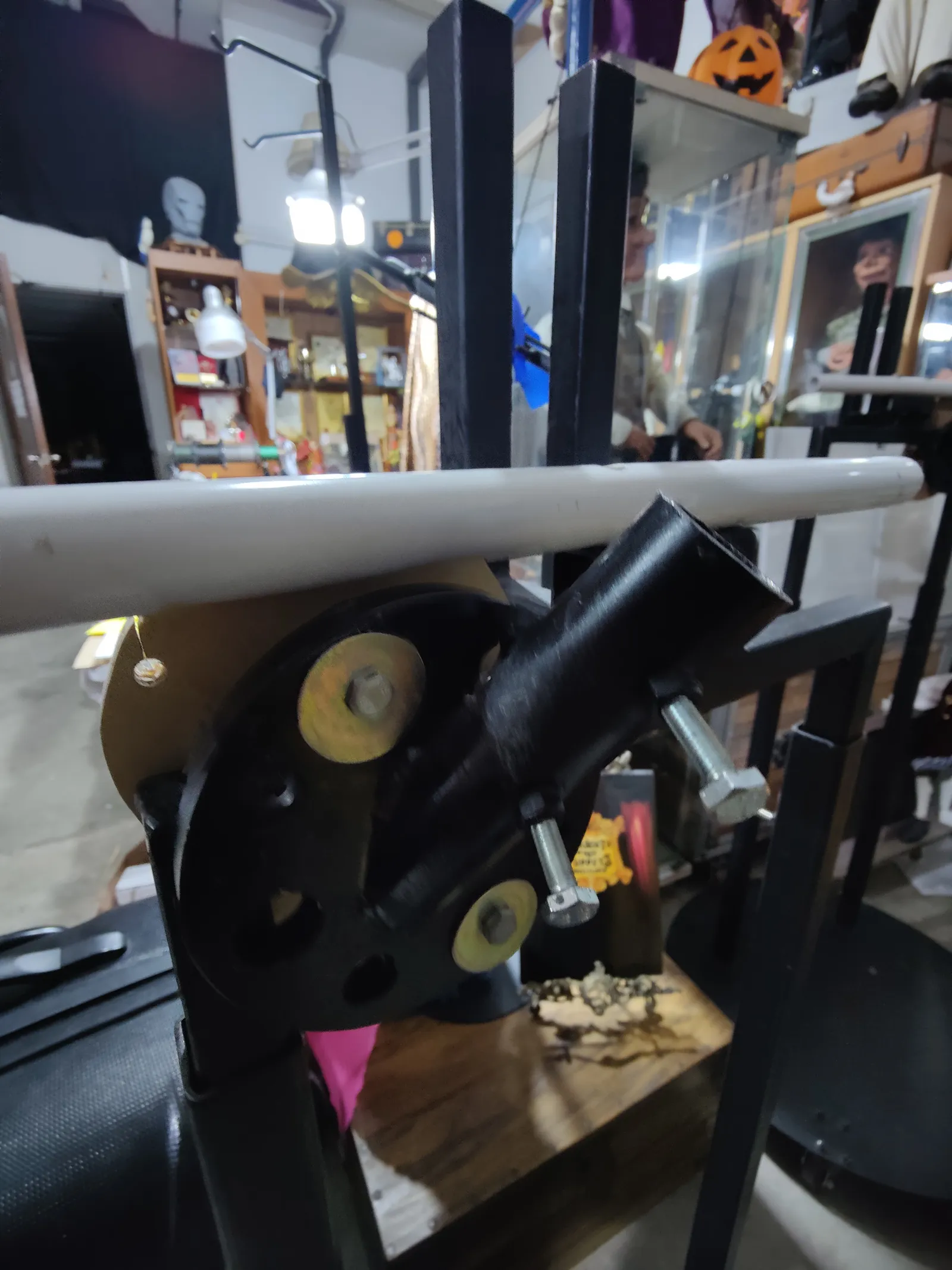 A black metal wall bracket with its angled tube, bolted onto a test frame in the studio