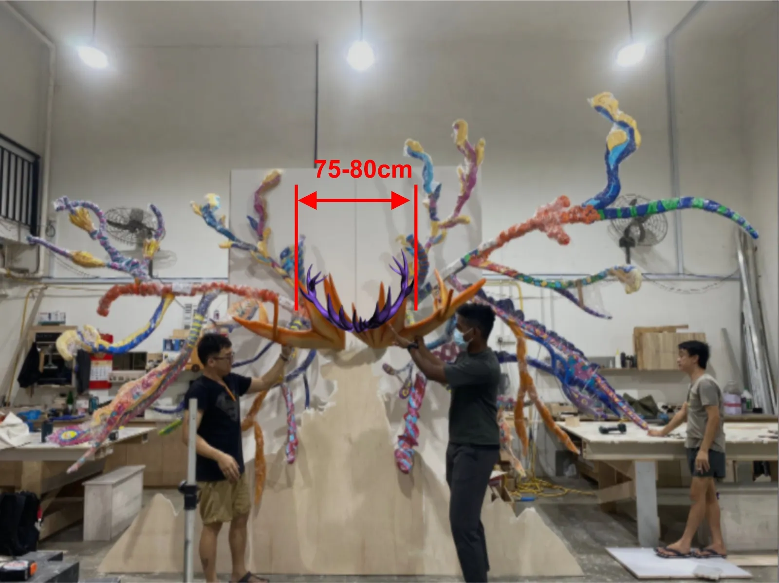The team dry-fitting the antlers on a studio wall, with the gap between the centre antler's tips marked at 75 to 80 cm