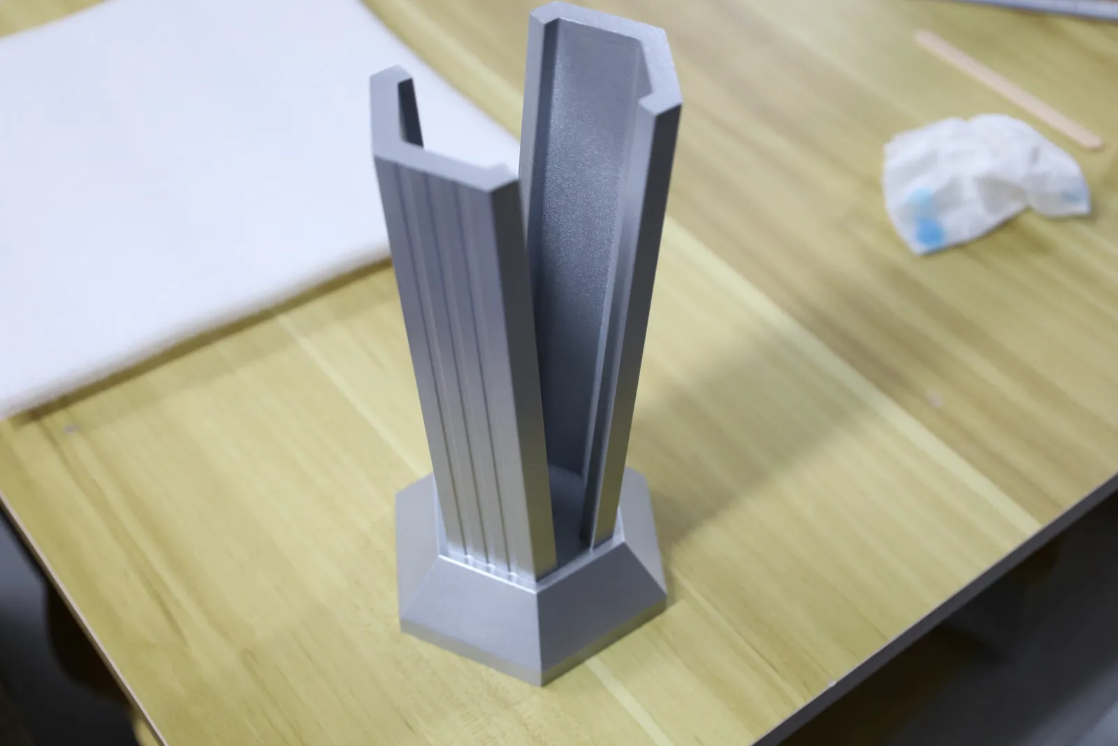 The fluted pillar and hexagonal base standing on a workbench, open at the front where the glove's stem slots in