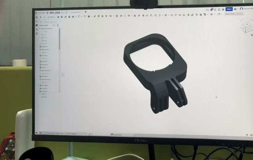 The bracket's 3D model on a monitor in CAD: a square frame with mount fingers below it