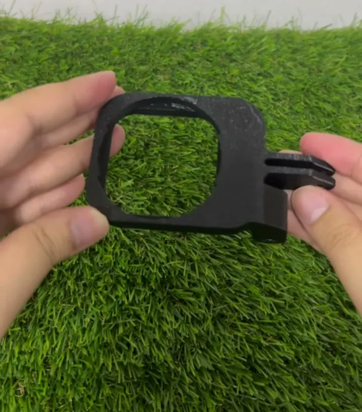 A black 3D printed version of the frame held in two hands, showing its mount fingers