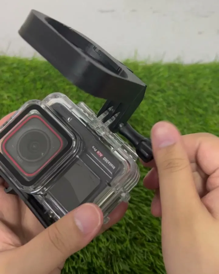 The black bracket bolted to the clear dive housing, its lens ring swinging down over the camera