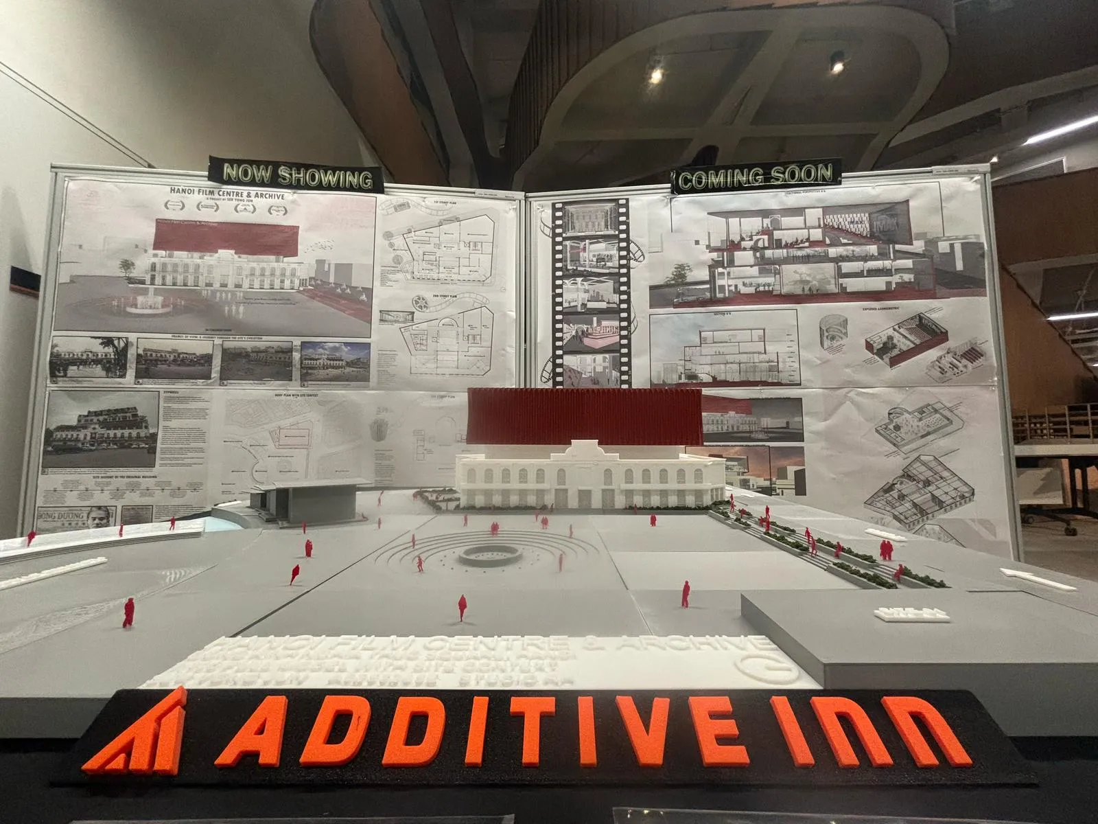 The site model in front of his presentation boards headed Now Showing and Coming Soon, with the name plate along the front edge