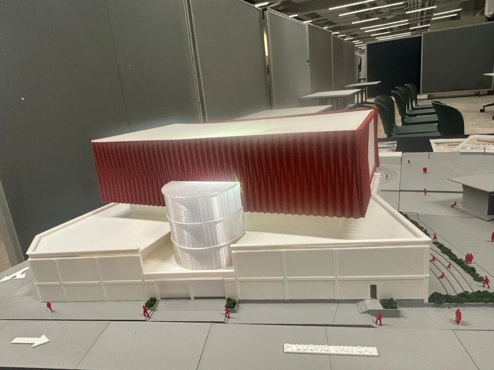 The back of the building: white walls, the red fluted block above and a clear round drum in front of it