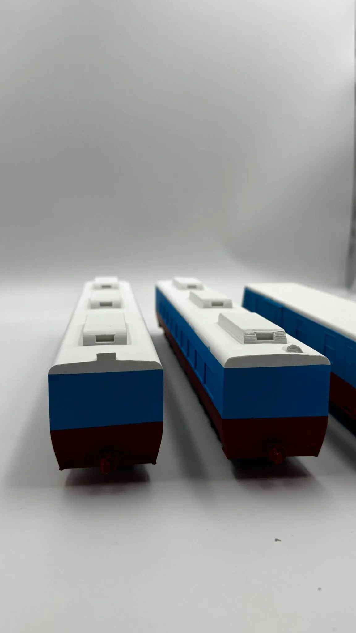 The ends of the train cars side by side, blue sides above red underframes, each with a red coupler