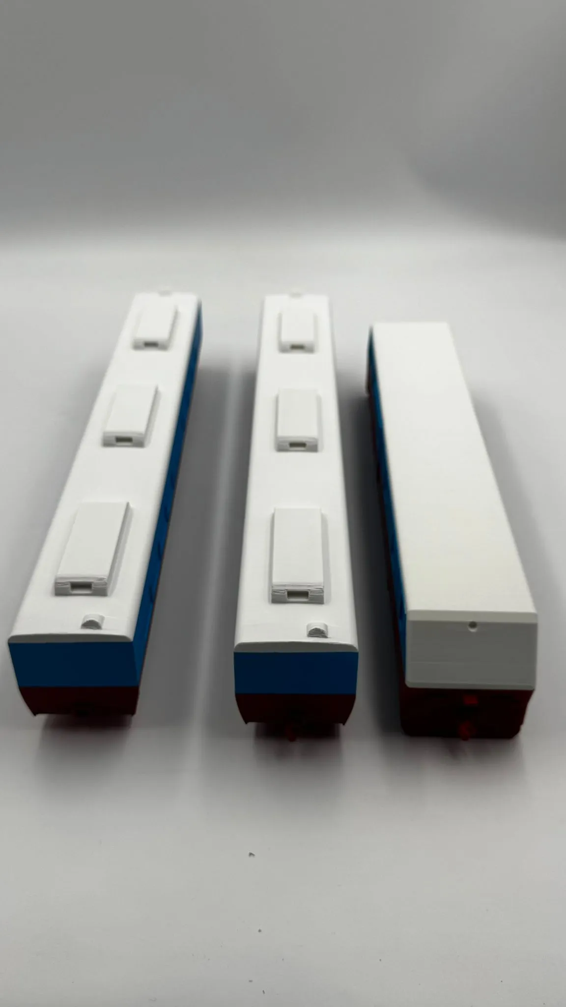 The three finished train cars lined up end on, two with vented roofs and one with a plain white roof