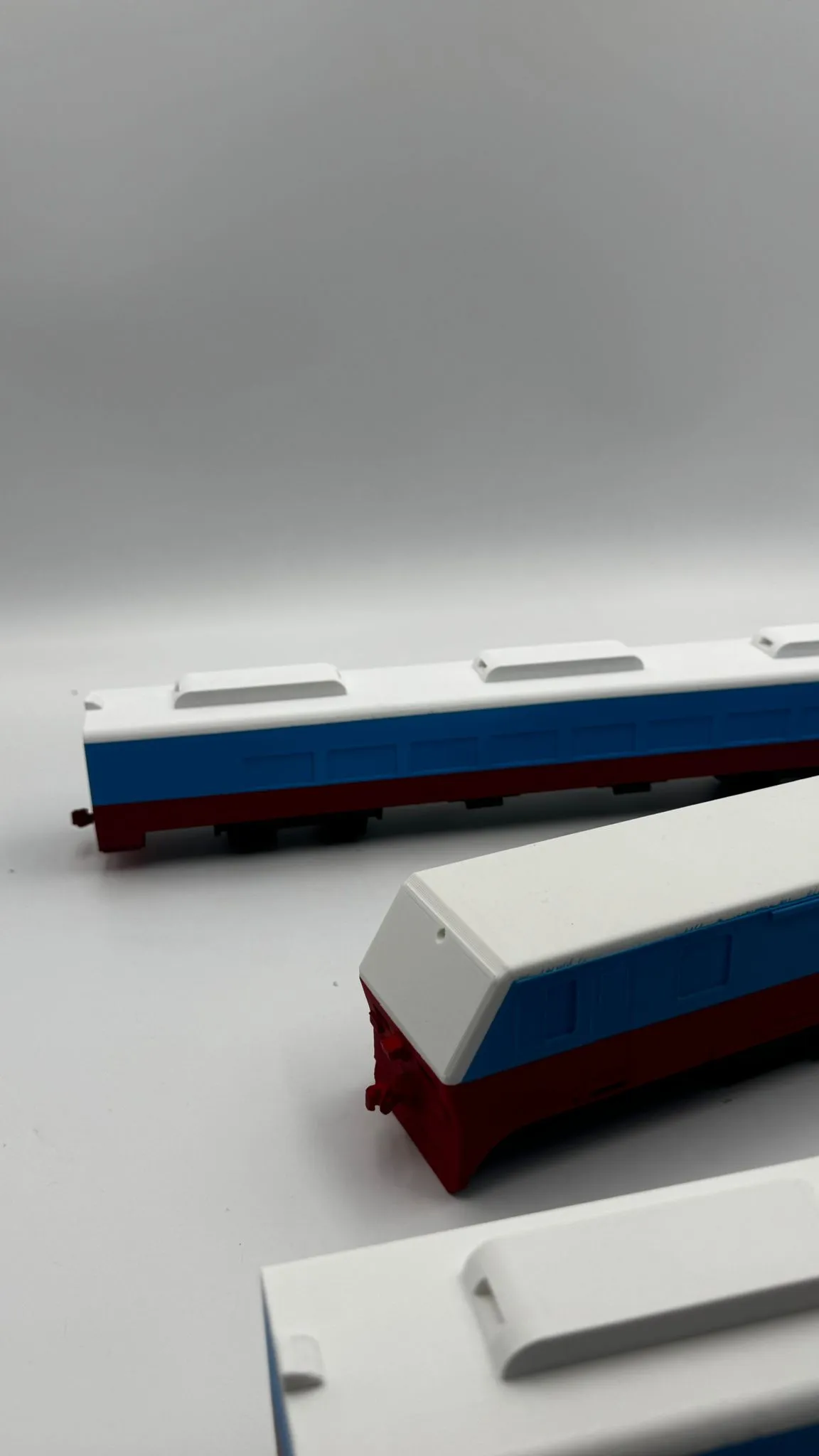 The finished train cars at an angle, showing the blue window band and red underframe of each