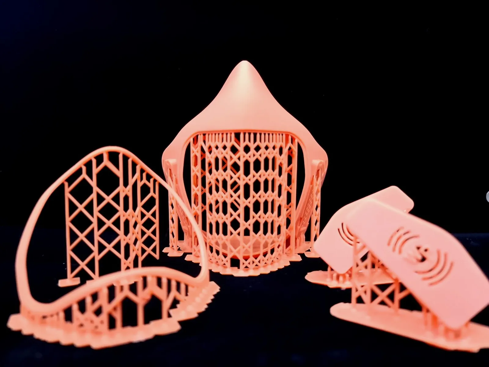 The orange resin mask body, visor frame and two vent covers standing on their lattice of print supports against a black background