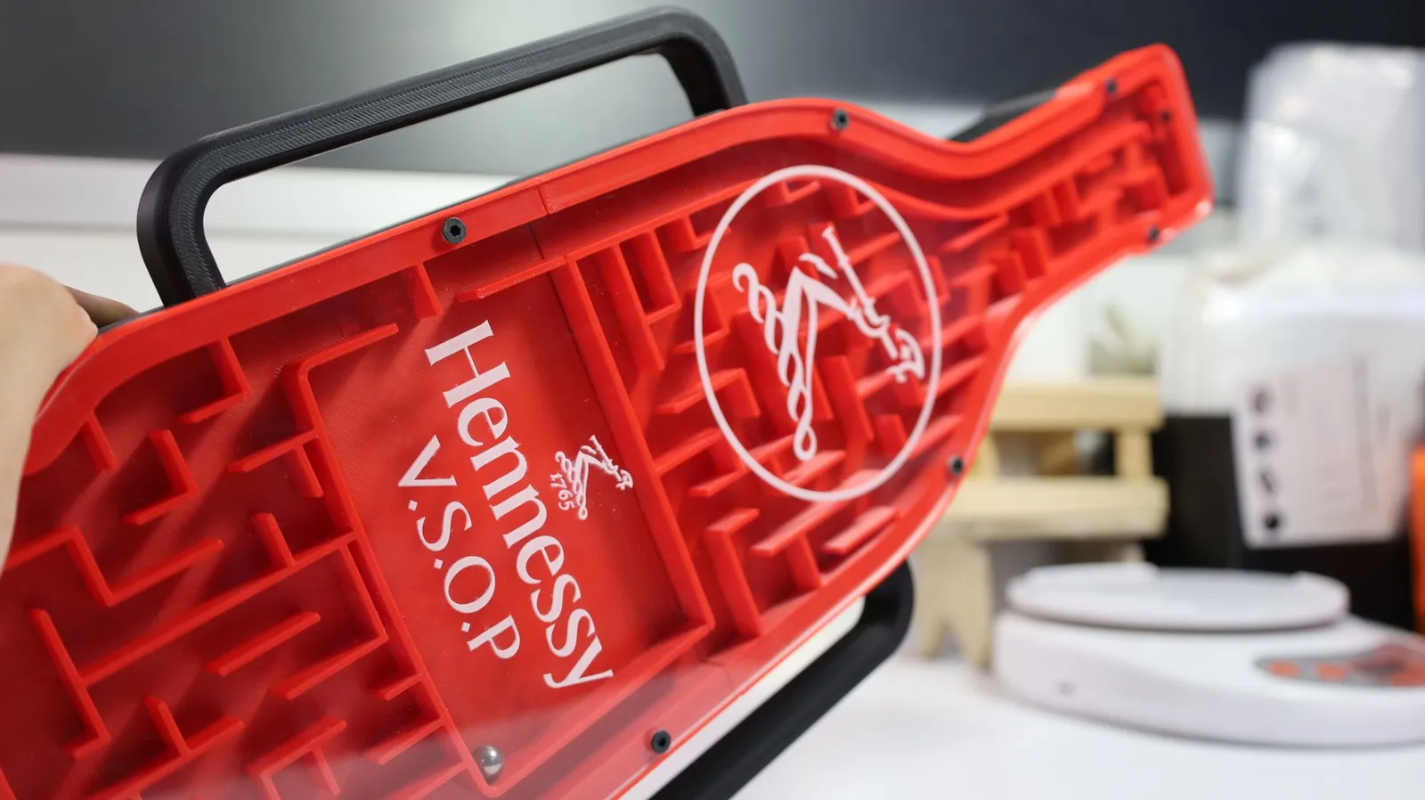 The maze tilted in a hand, showing the rider emblem and the V.S.O.P panel over the red maze channels
