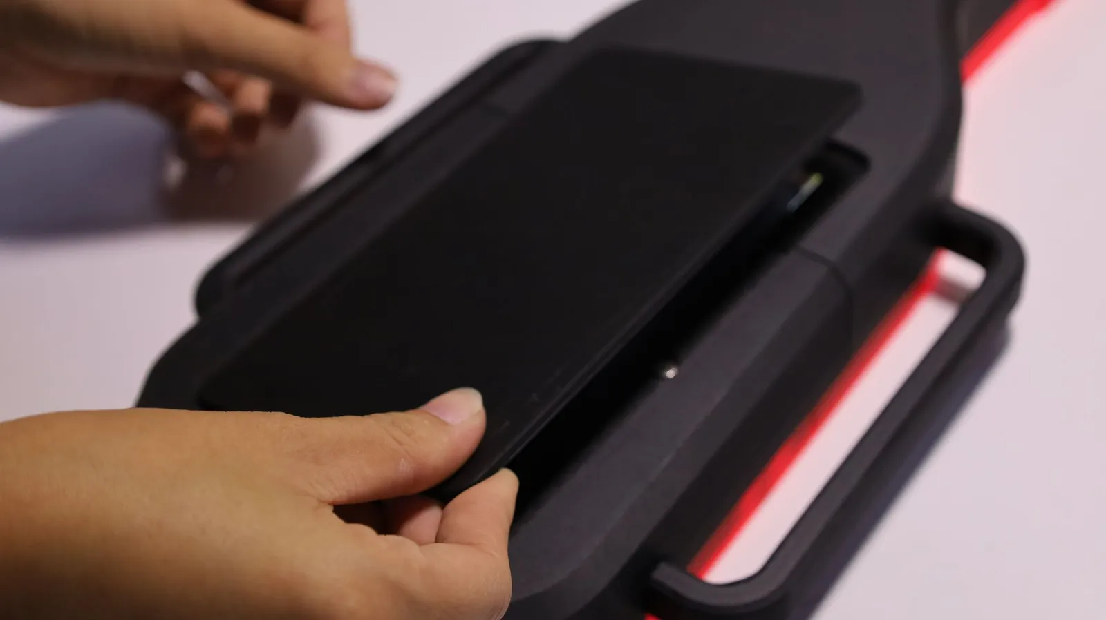 Hands setting the black magnetic cover back over the battery bay on the underside of the maze