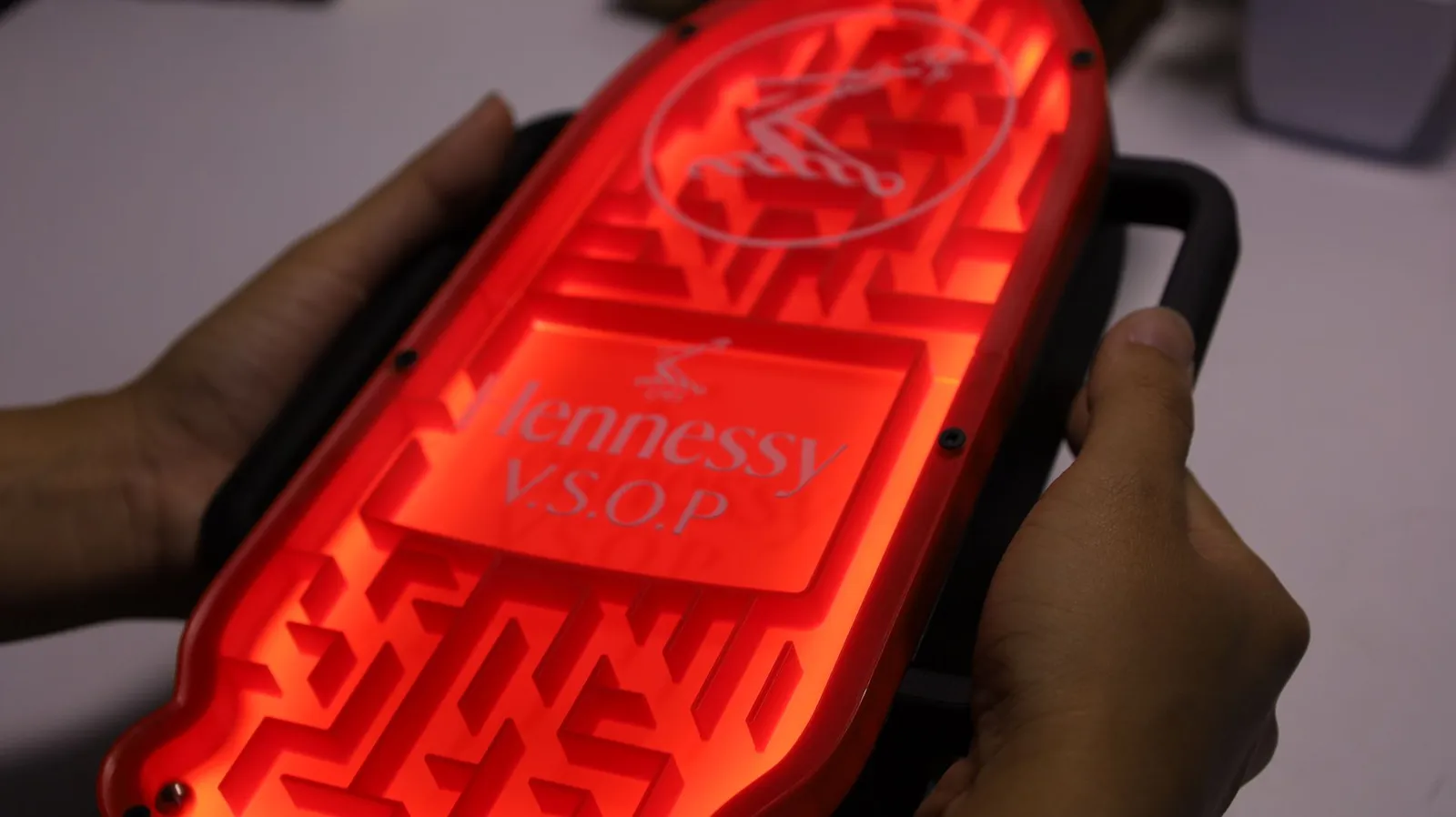 Two hands holding the lit maze by its side handles, ready to tilt it