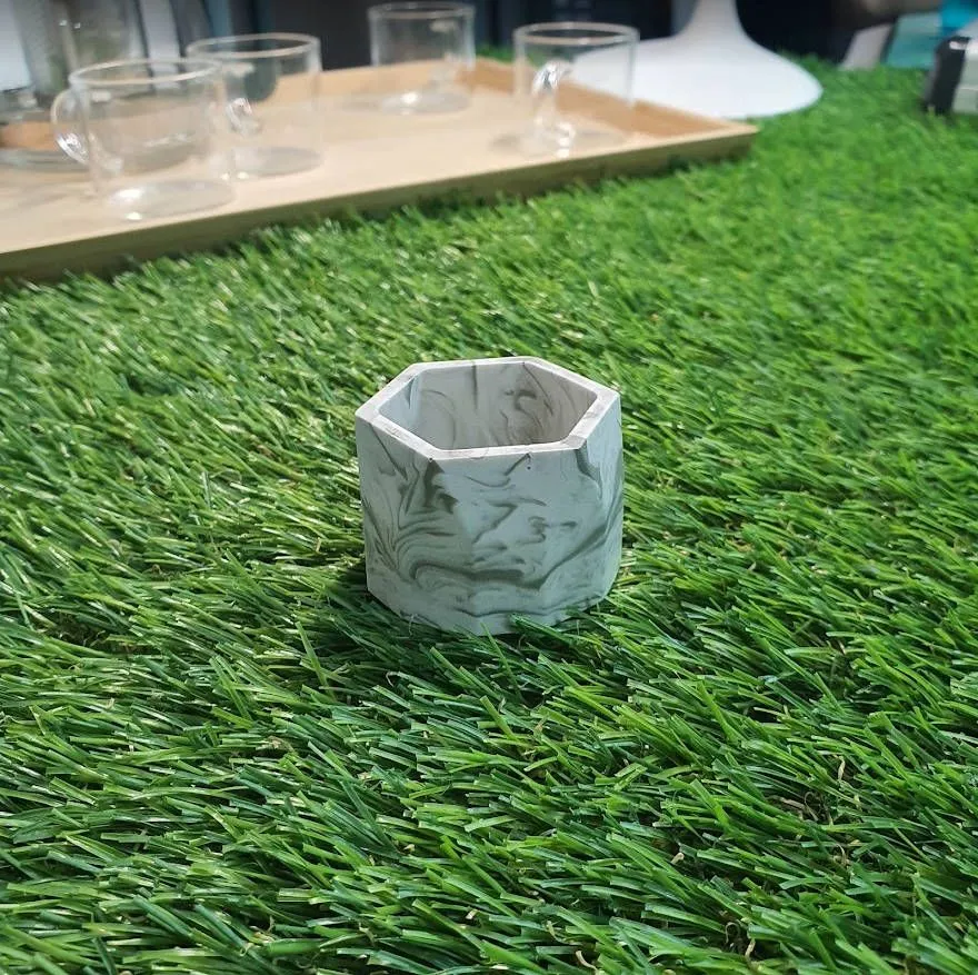 A hexagonal Jesmonite planter with soft green swirls through white
