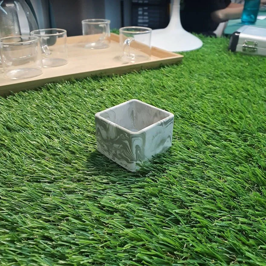 A square Jesmonite planter with pale green swirls through white