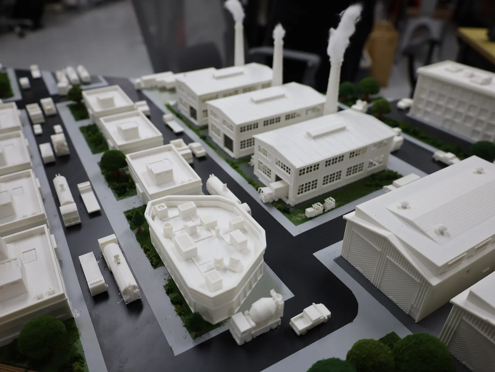 An industrial street with trucks parked along it, factory sheds, a curved building and a cement mixer on the corner