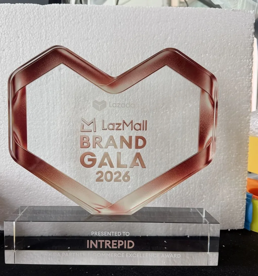 A single finished heart award on its clear base, reading LazMall Brand Gala 2026 and PRESENTED TO INTREPID, held against a white foam board