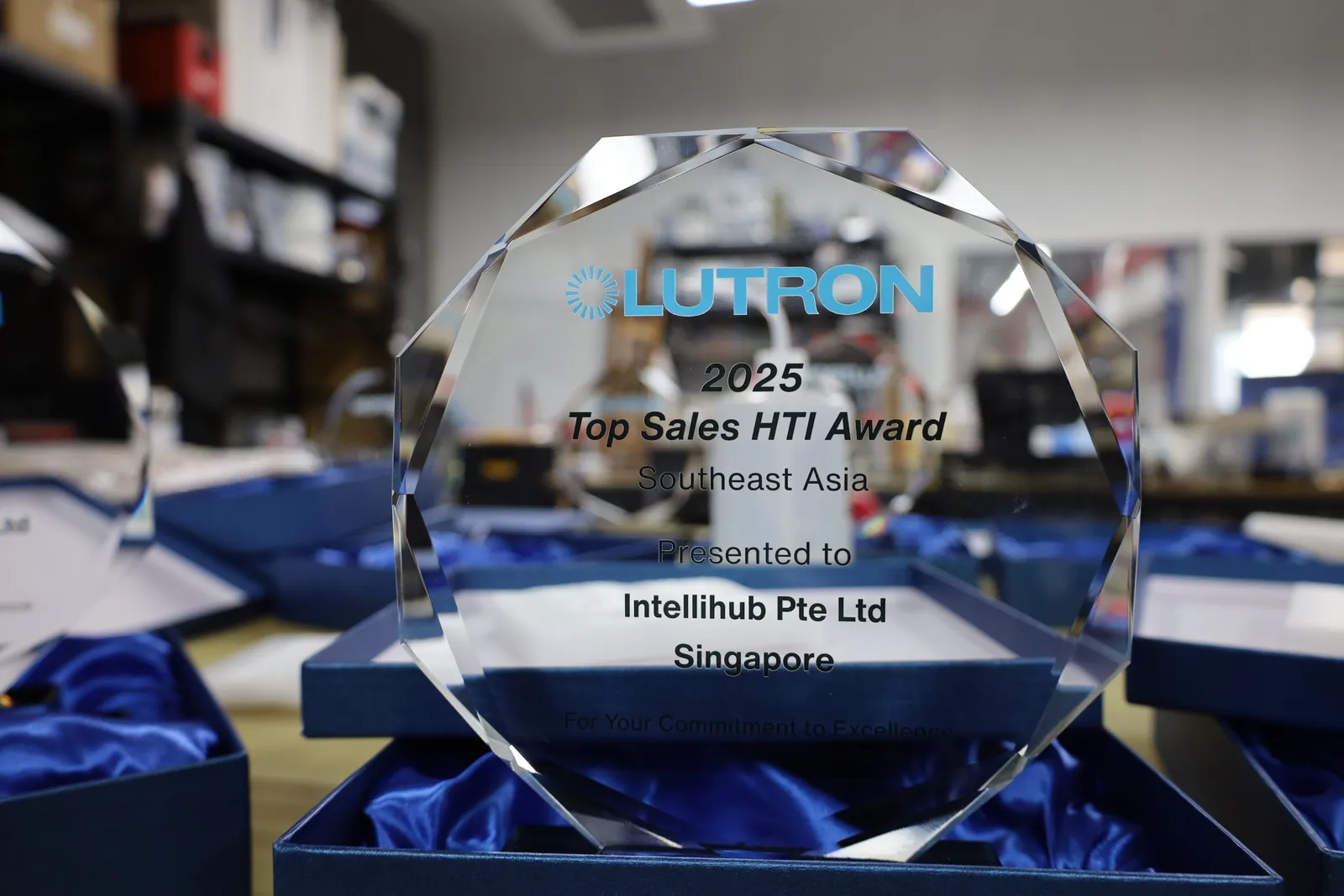 A faceted glass award with the Lutron logo in blue, lettered 2025 Top Sales HTI Award, Southeast Asia, presented to Intellihub Pte Ltd, Singapore