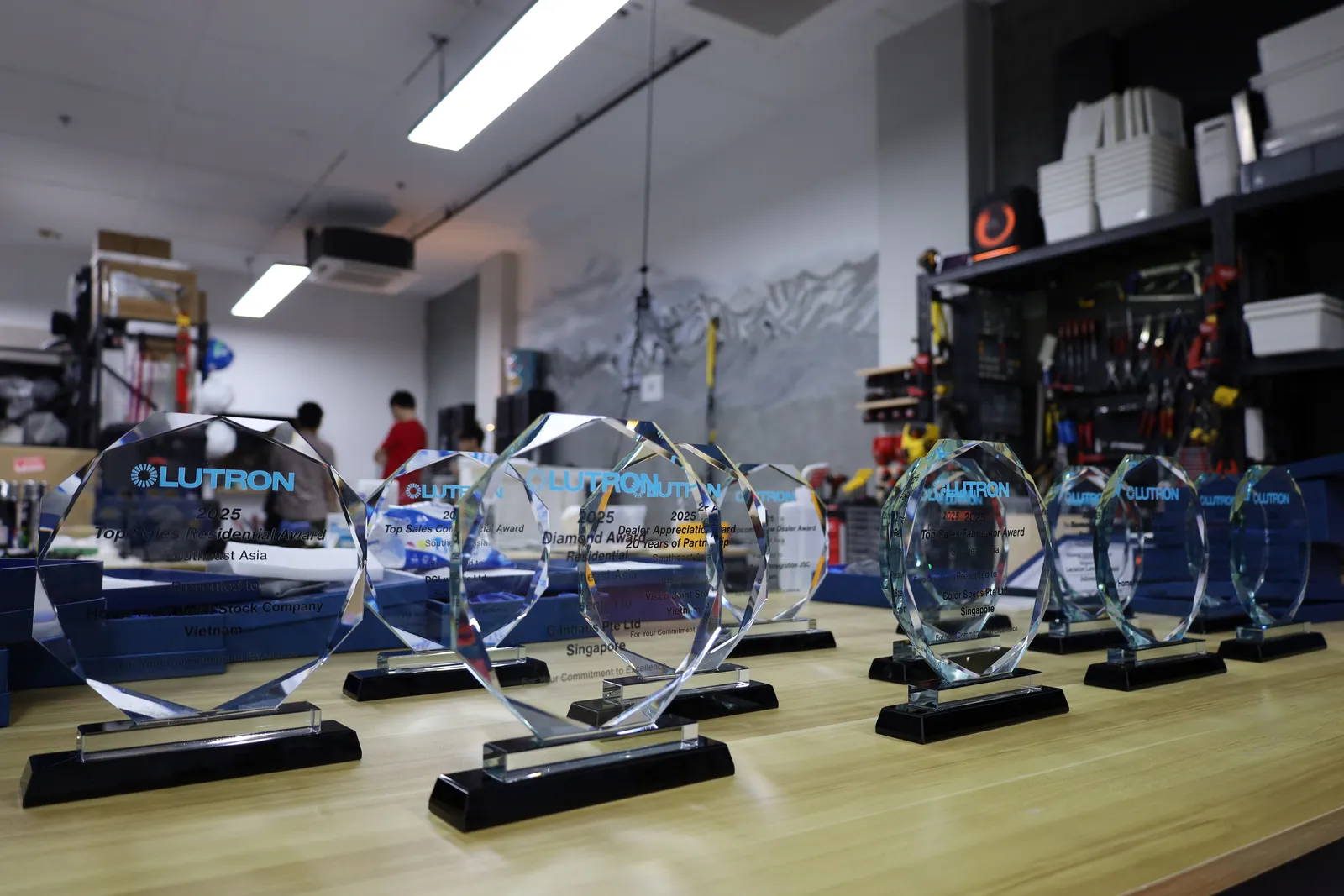 A row of faceted glass Lutron awards on black bases along a workbench, seen low down