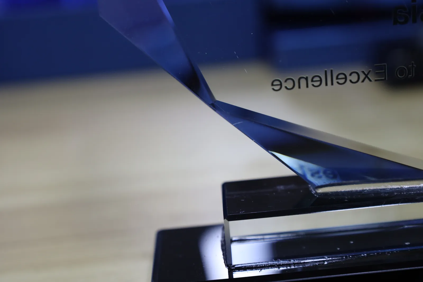 The faceted foot of a glass award seated in a clear block on a glossy black base