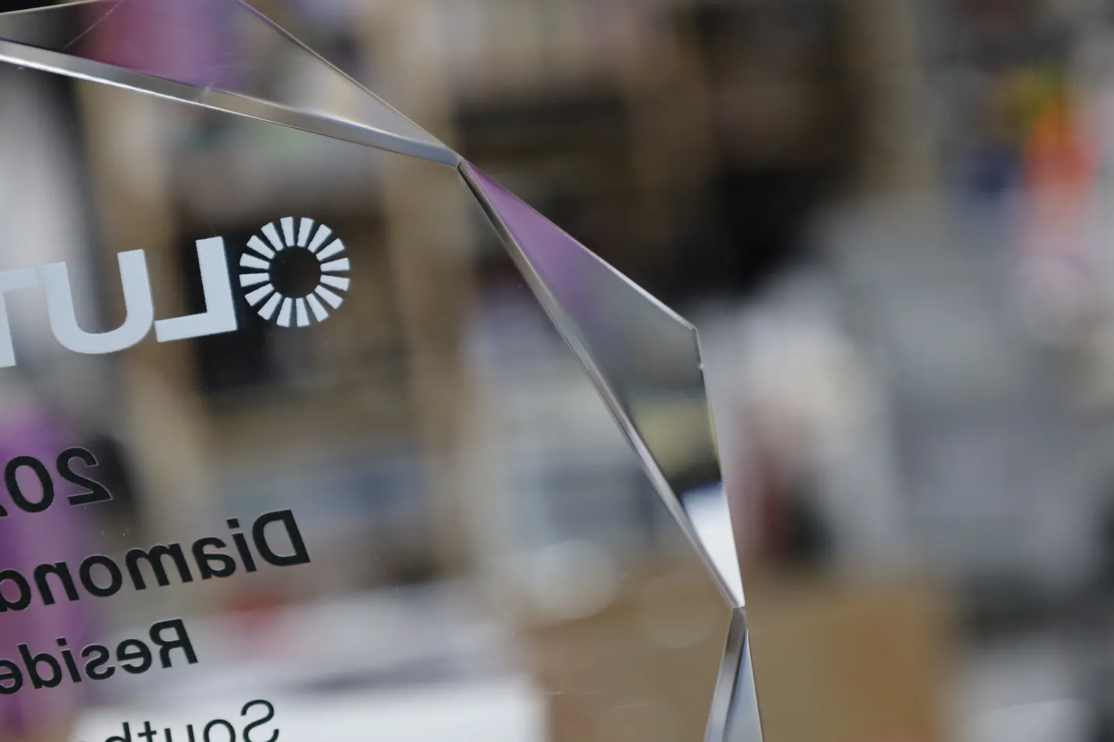 The Lutron logo and the words 2025 Diamond Award seen in reverse through the back of a faceted glass award