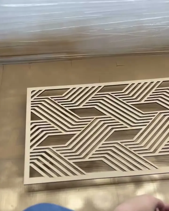 A bare wood panel cut in bands of diagonal stripes, lying on the floor of our spray booth