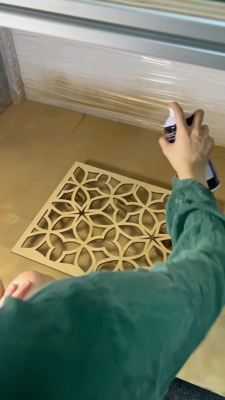 A team member spraying gold over the petal pattern panel on the floor of the spray booth