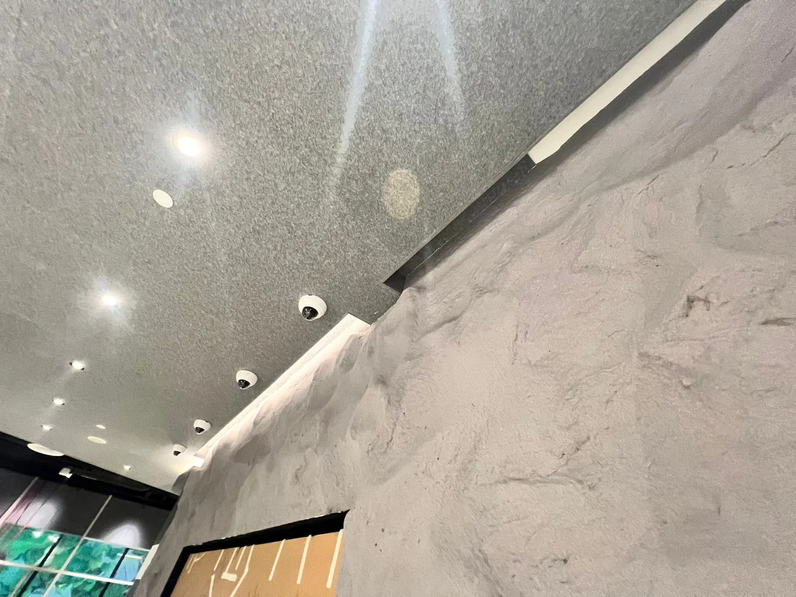 Looking up the stone feature wall, its rugged rock texture rising to the ceiling lights