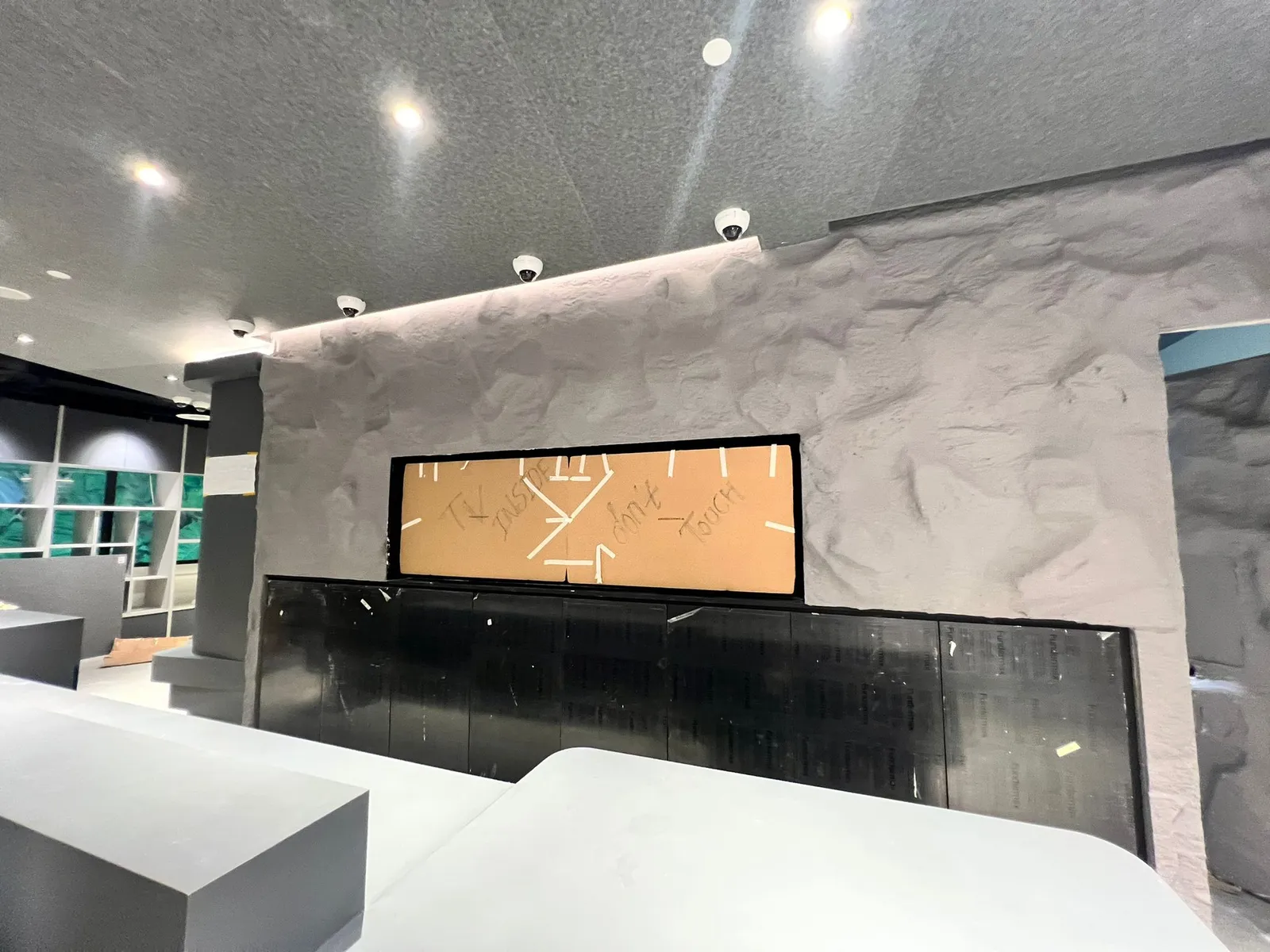 The stone feature wall rising behind the counter, its rock texture framing a display window and dark panels