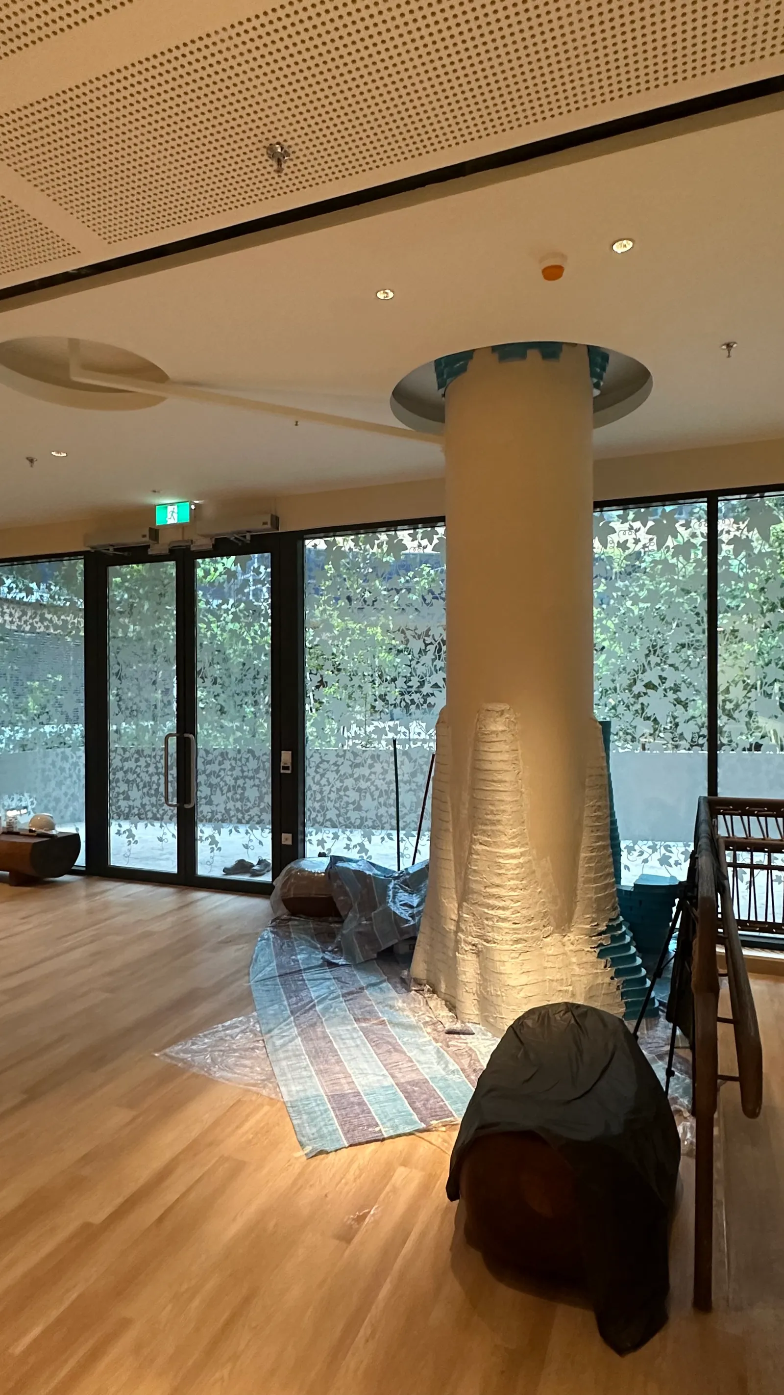 The reception tree trunk taking shape around a pillar, its lower half textured, dust sheets on the wooden floor