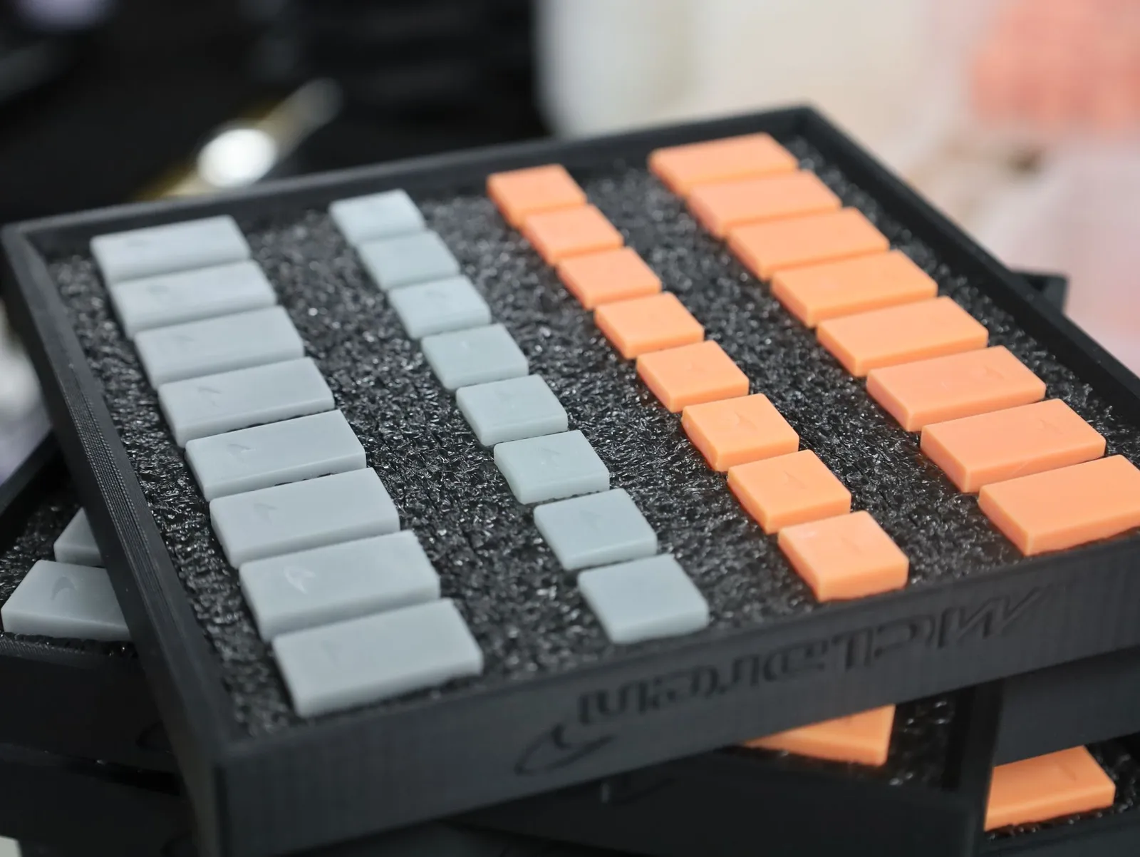 Close-up of a finished tray: grey and orange pieces in rows on black foam, the McLaren name and logo printed into the rim