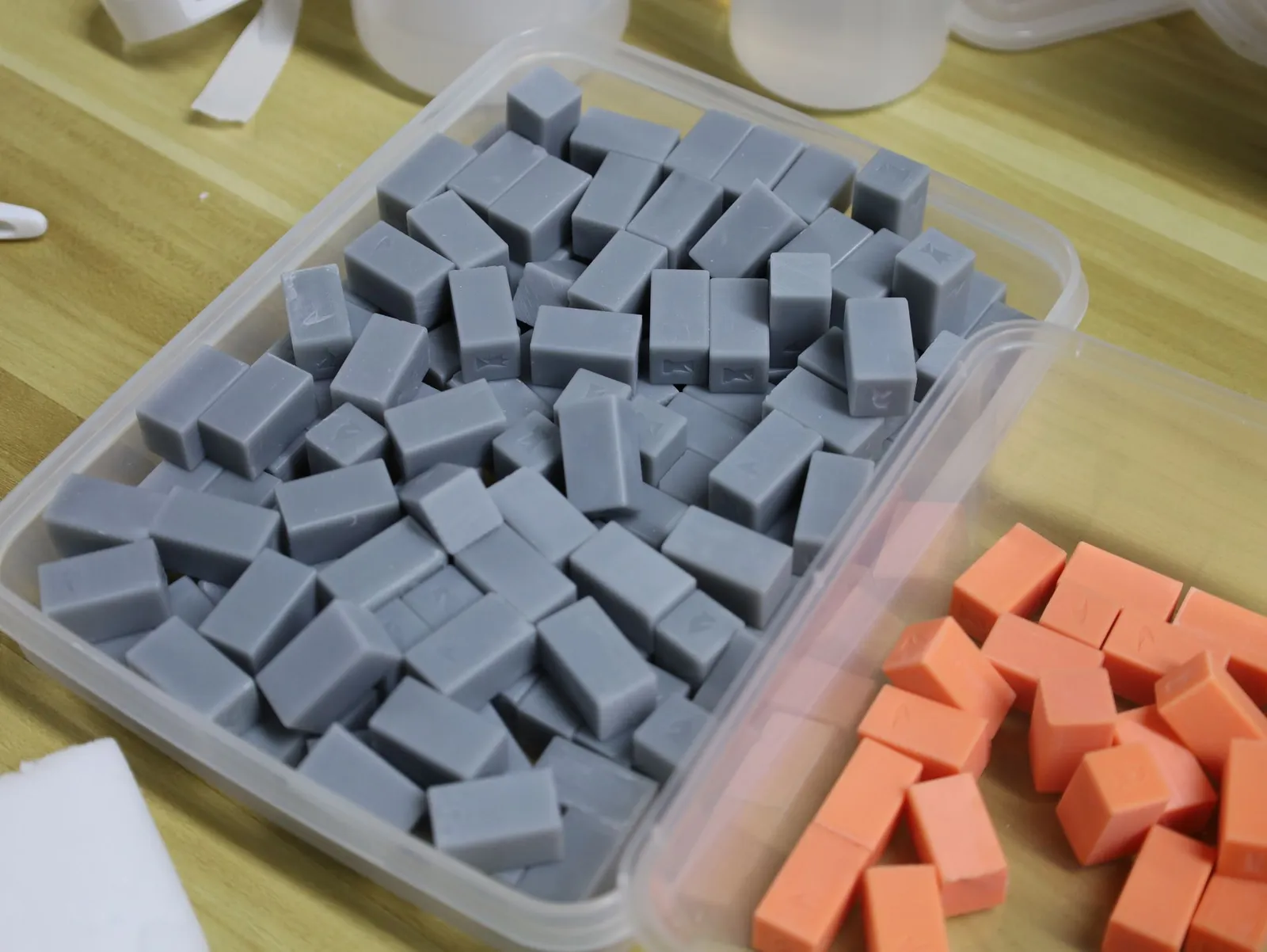 A tub full of grey chess pieces, with orange pieces beside it