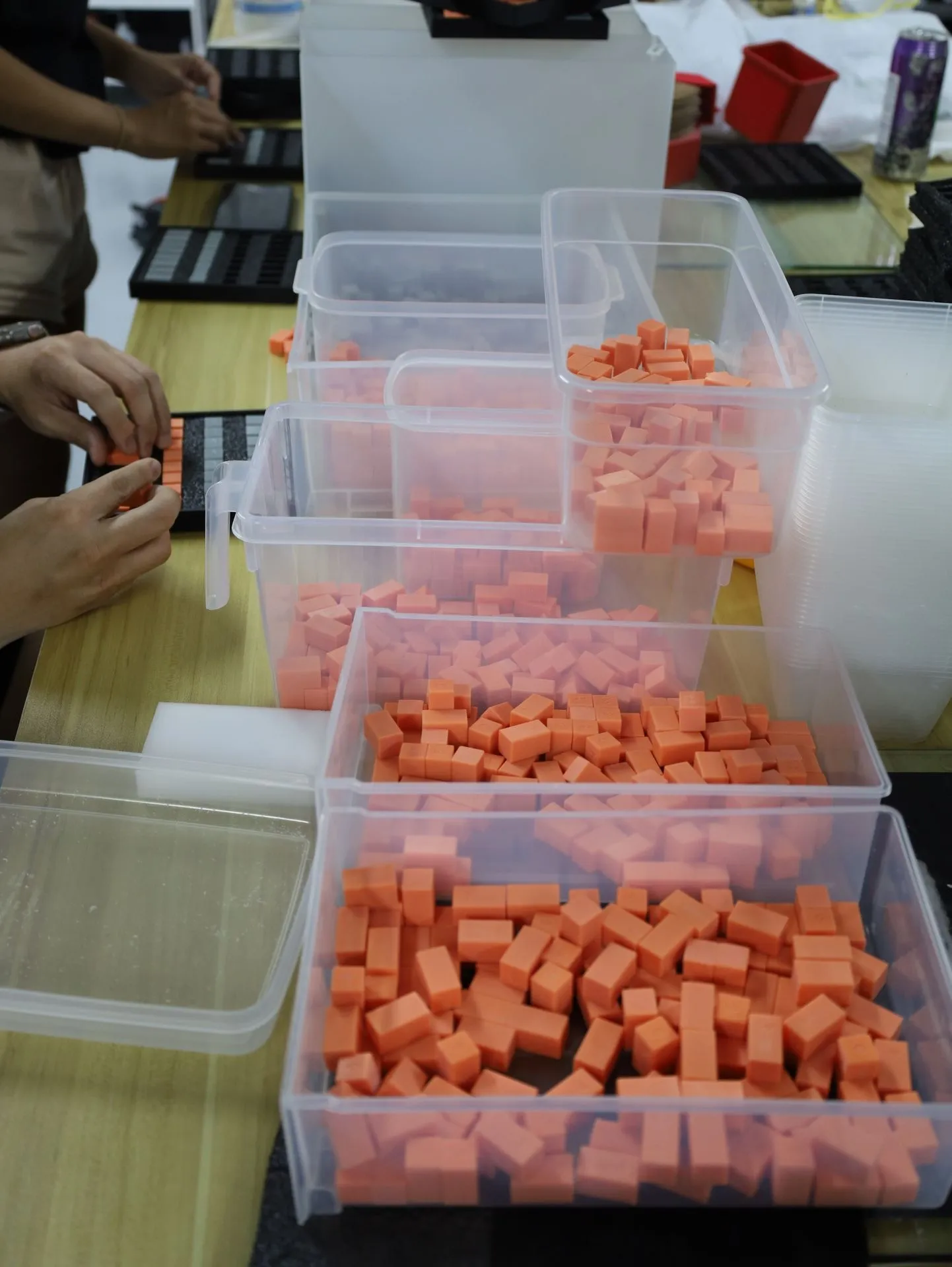 The team filling trays from tubs of orange pieces on a long workbench
