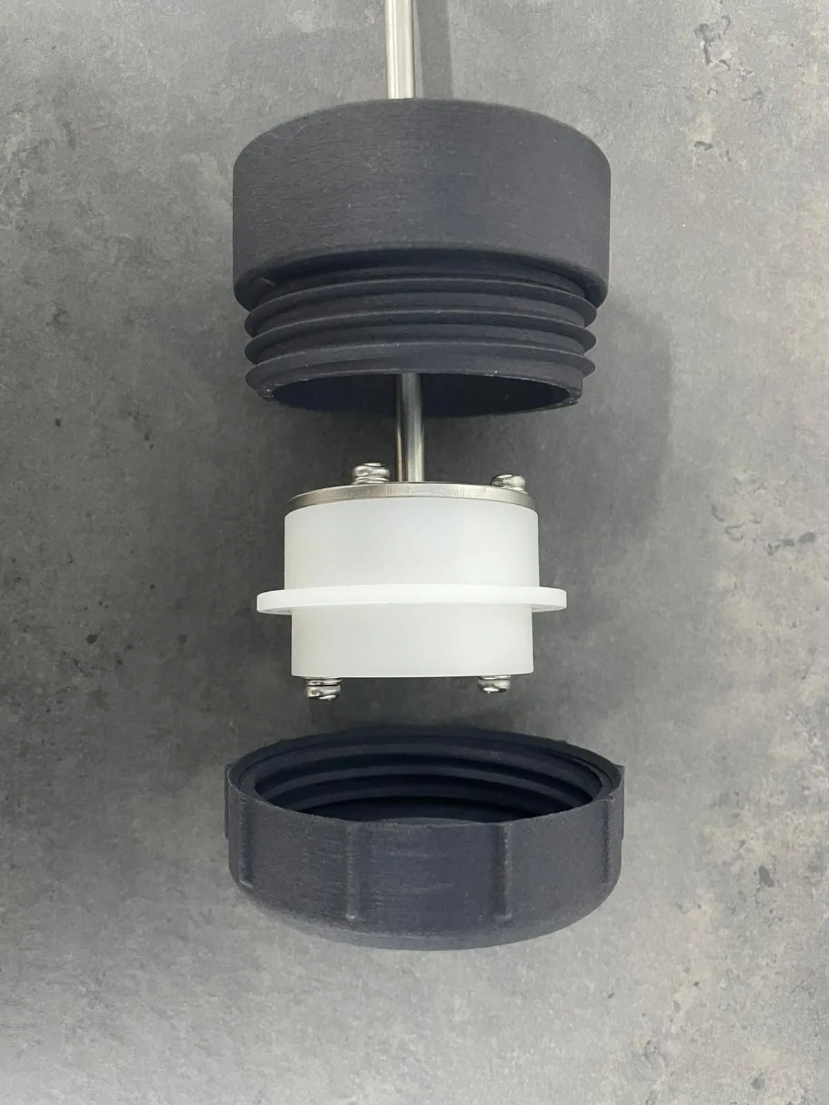 The set taken apart: the black attachment with its outer thread, the white fitting held by a steel ring and screws, and the ring cap below