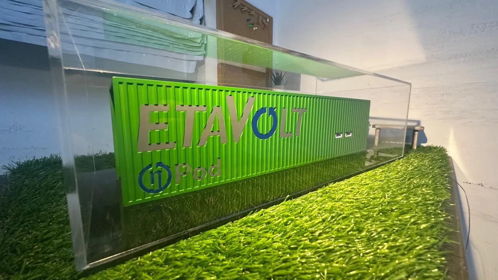 The green EtaVolt container model under a clear rectangular cover, seen from one end