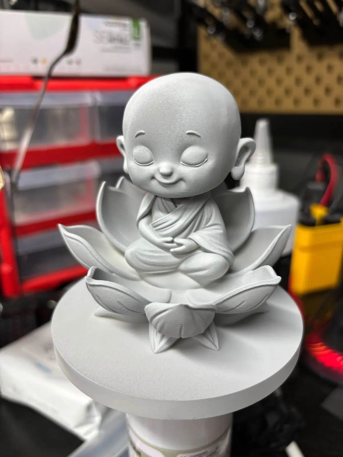 White resin print of a Mini Me monk figurine on its lotus base, before painting